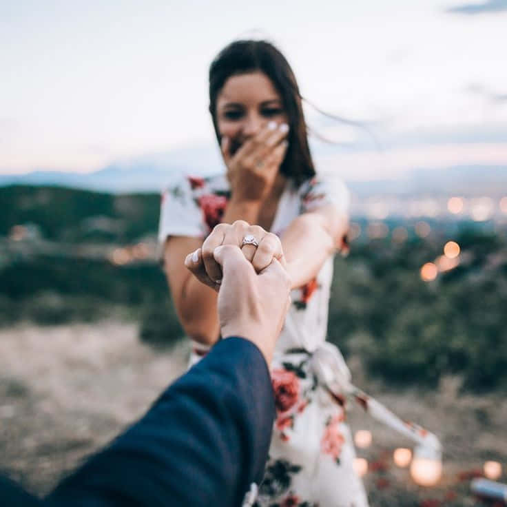 一位女性在黃昏時分的浪漫求婚中看到訂婚戒指時欣喜若狂。