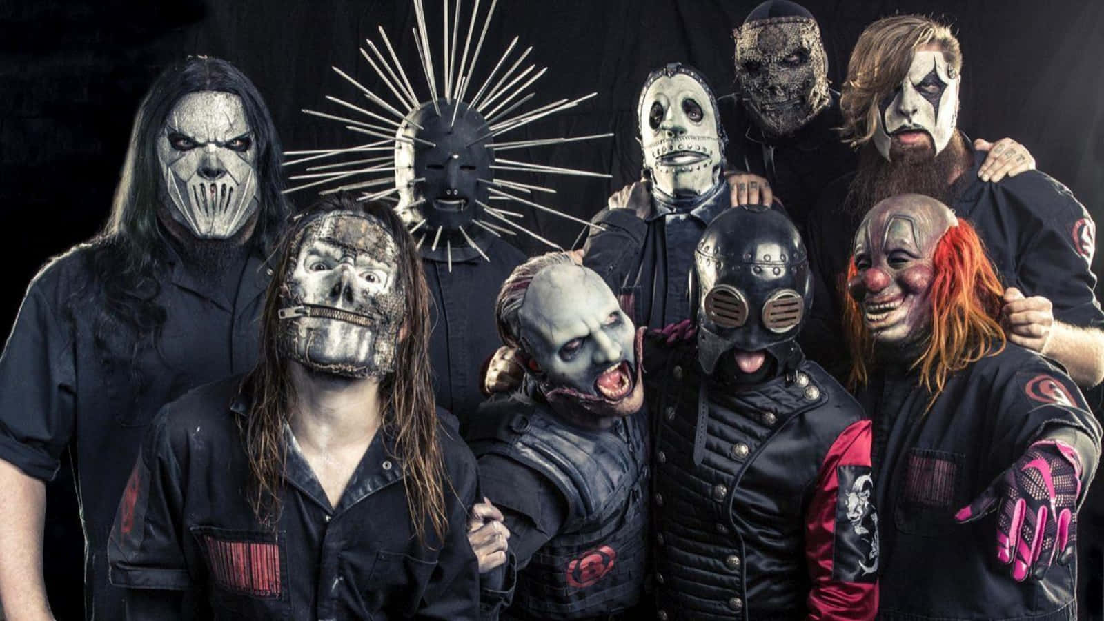 戴面具的Slipknot樂隊桌面壁紙 壁紙 — 一群戴著面具的音樂家，化著怪誕的妝容，穿著深色衣服，在黑色背景下強烈地擺姿勢。