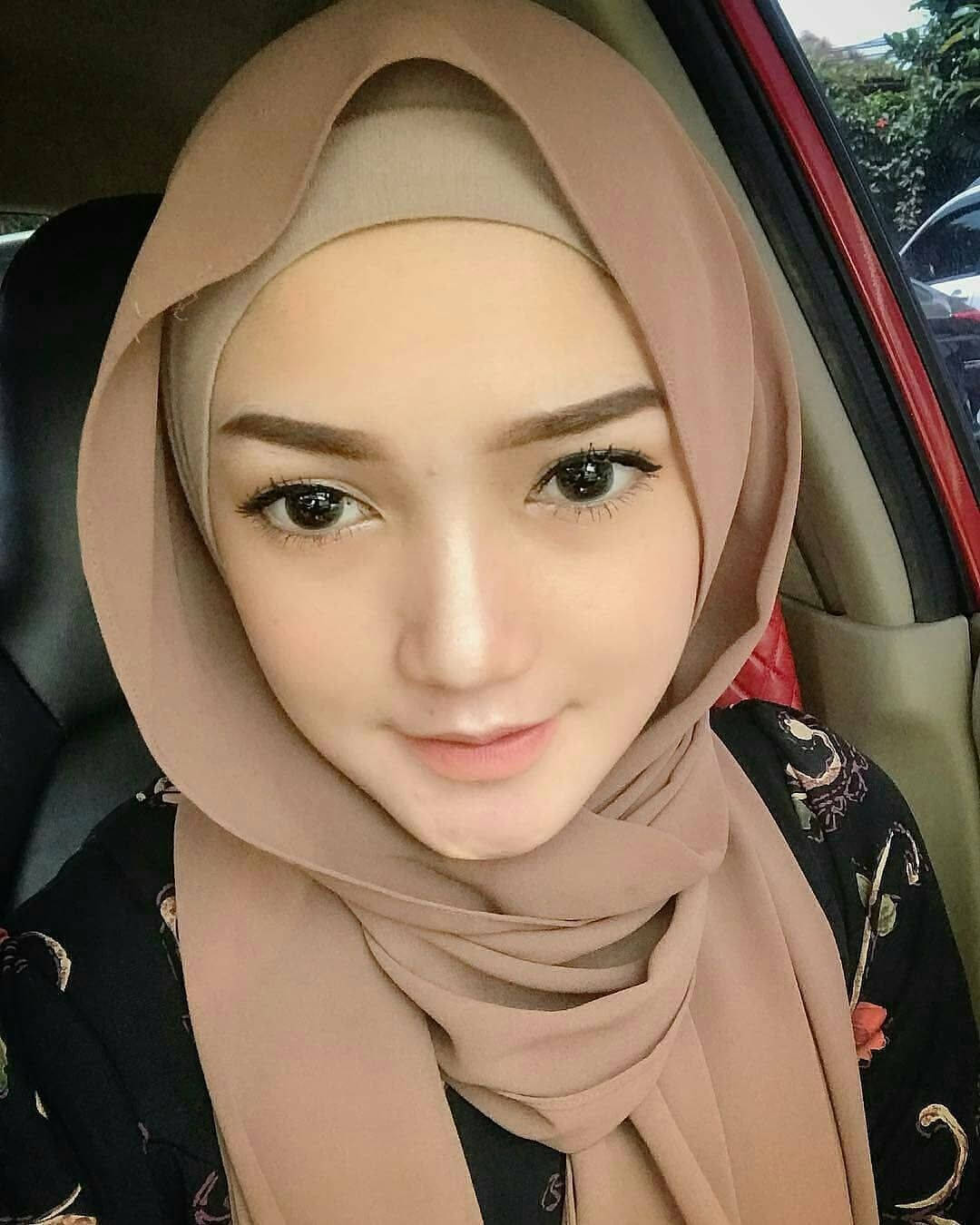 一位戴米色頭巾的女性在車內微笑。