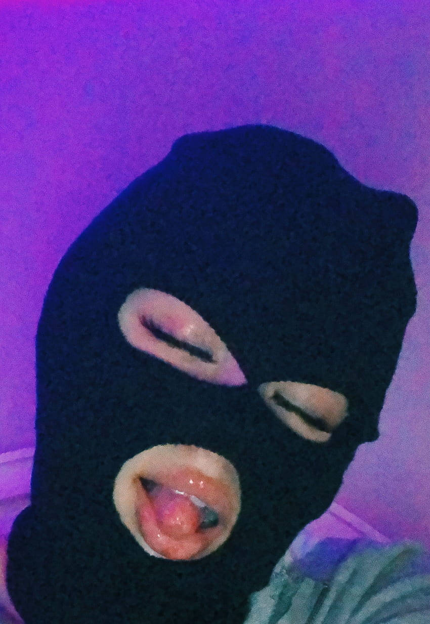 戴黑色巴拉克拉法帽的人在紫色燈光下伸出舌頭。