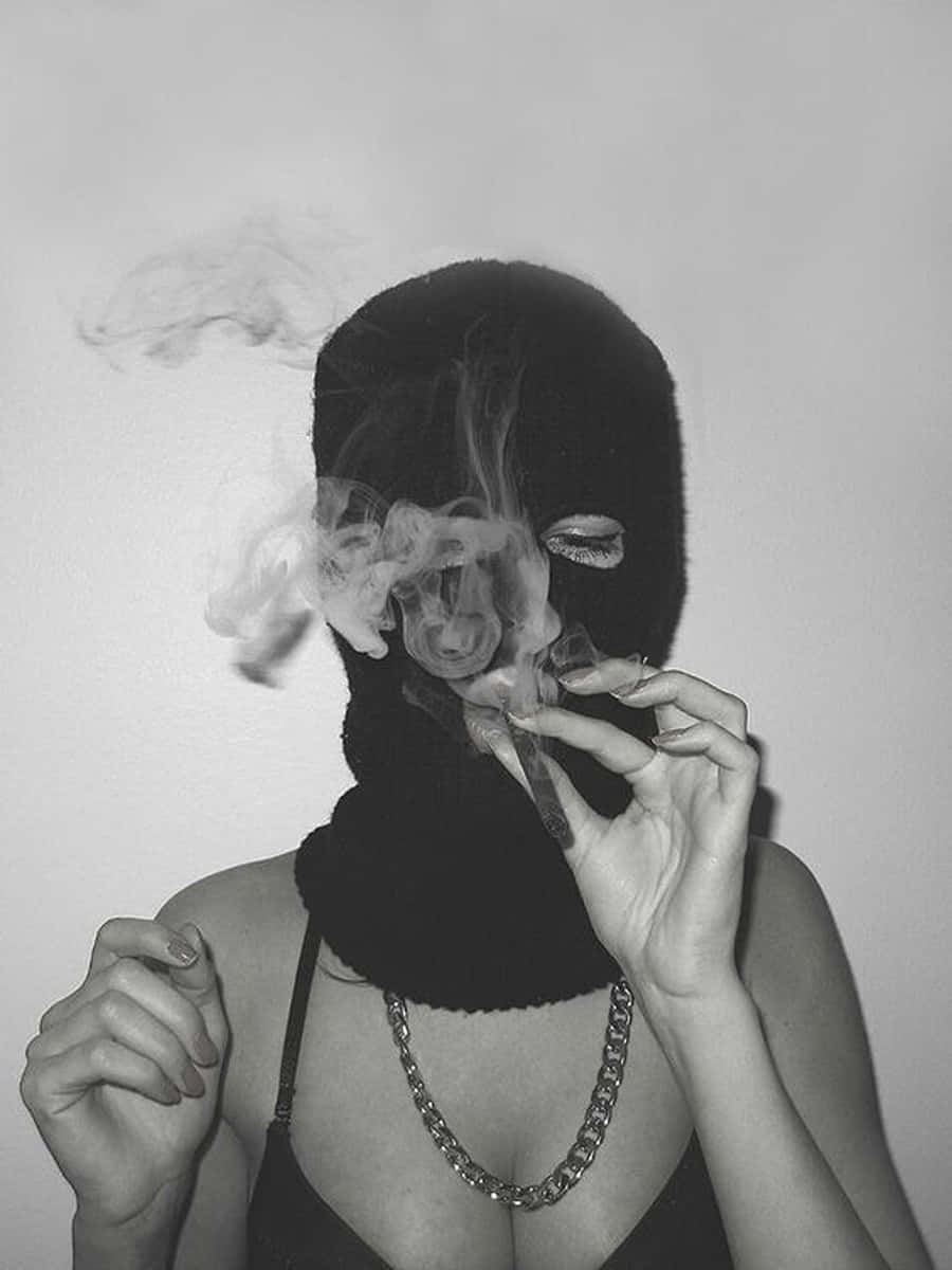 戴黑色頭套嘅人吸煙，煙霧喺臉周圍縈繞。
