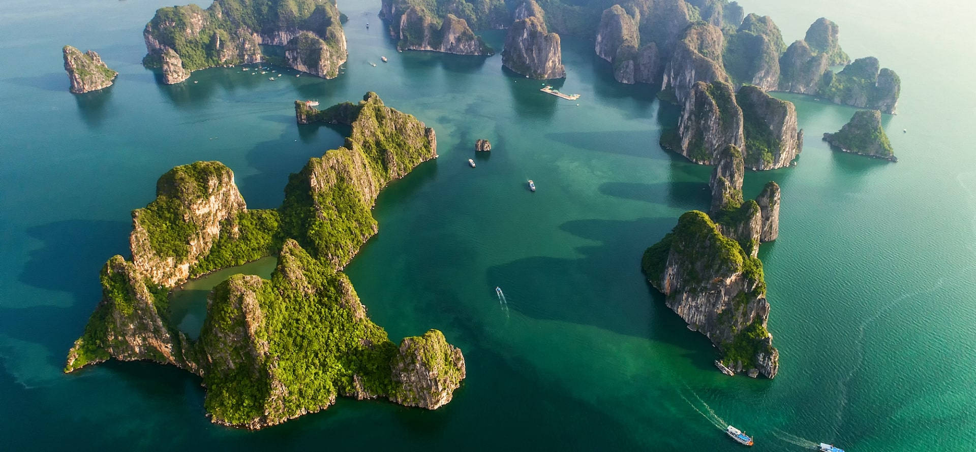 從空中俯瞰碧綠海水中鬱鬱蔥蔥的島嶼，有小船。