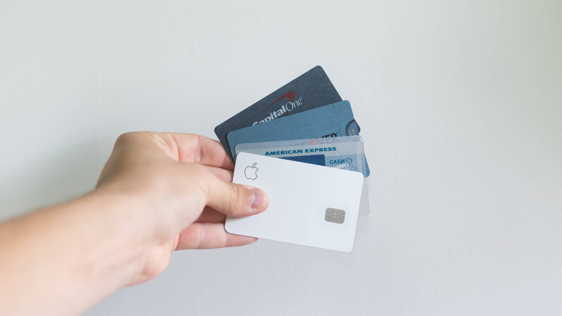 手持多張信用卡，包括Apple Card、Capital One和American Express。