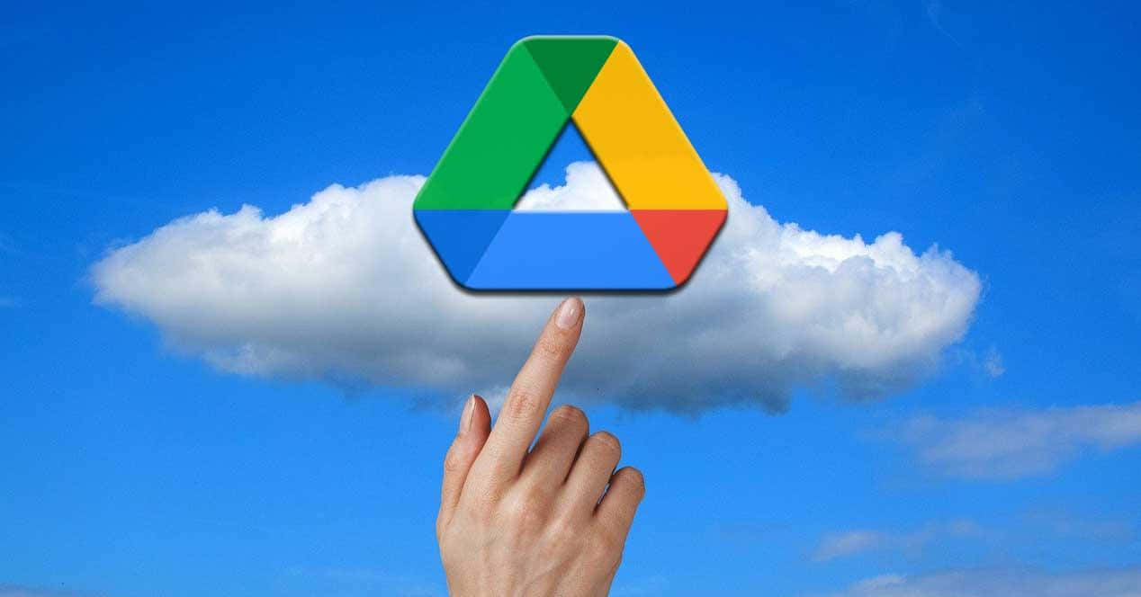 手指指向漂浮在藍天白雲上的 Google Drive 標誌。