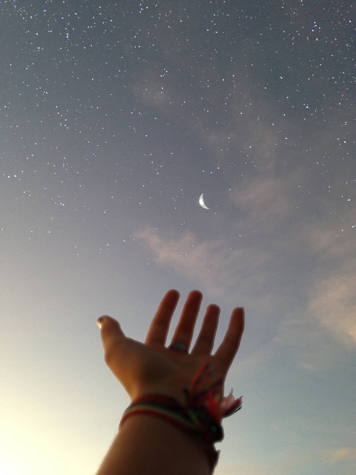 一個人的手伸向夜空中的星星和月亮。