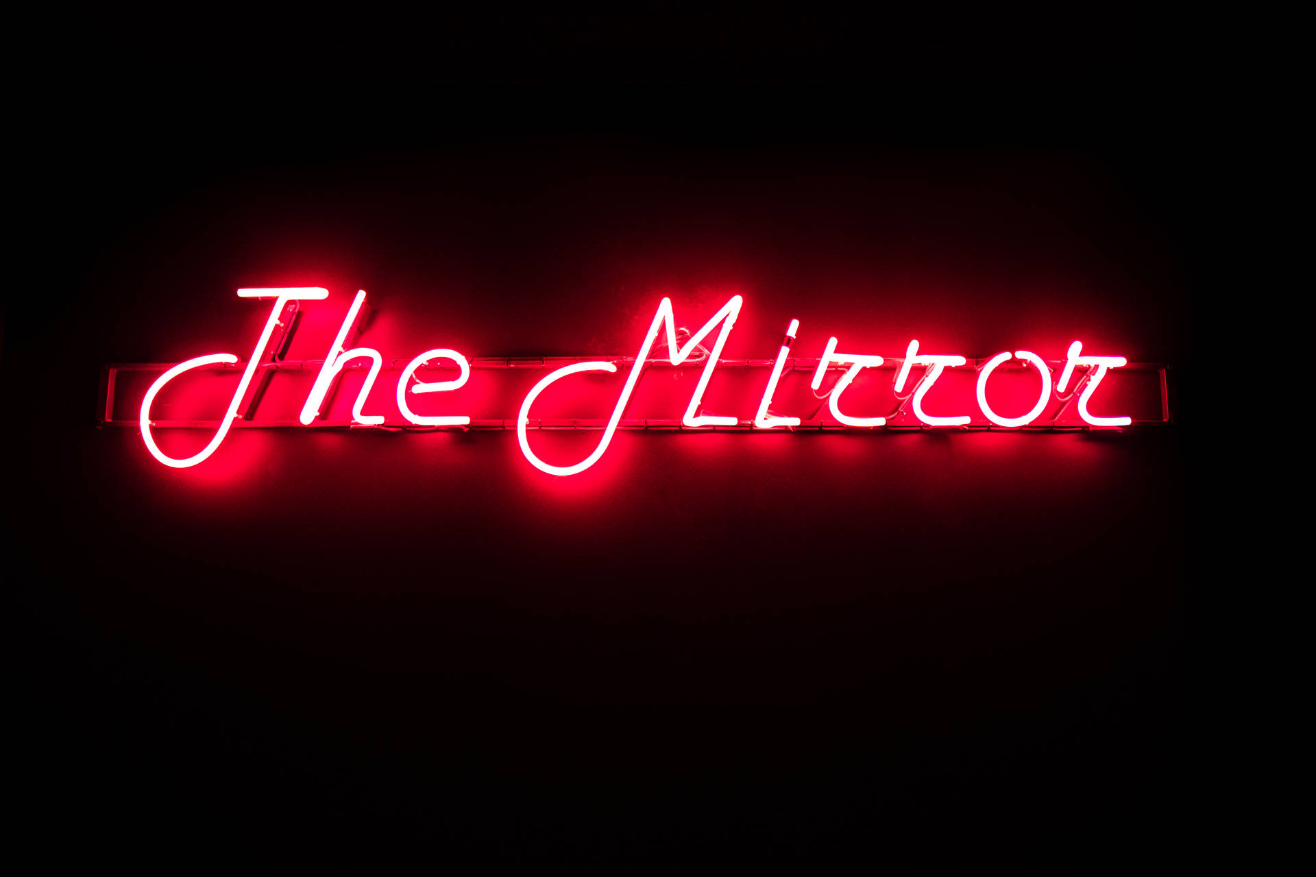 黑色牆上寫著「The Mirror」的紅色霓虹燈牌。