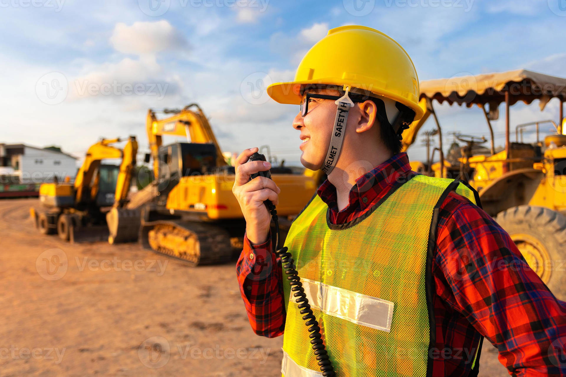建築工人在建築工地重型機械附近使用對講機