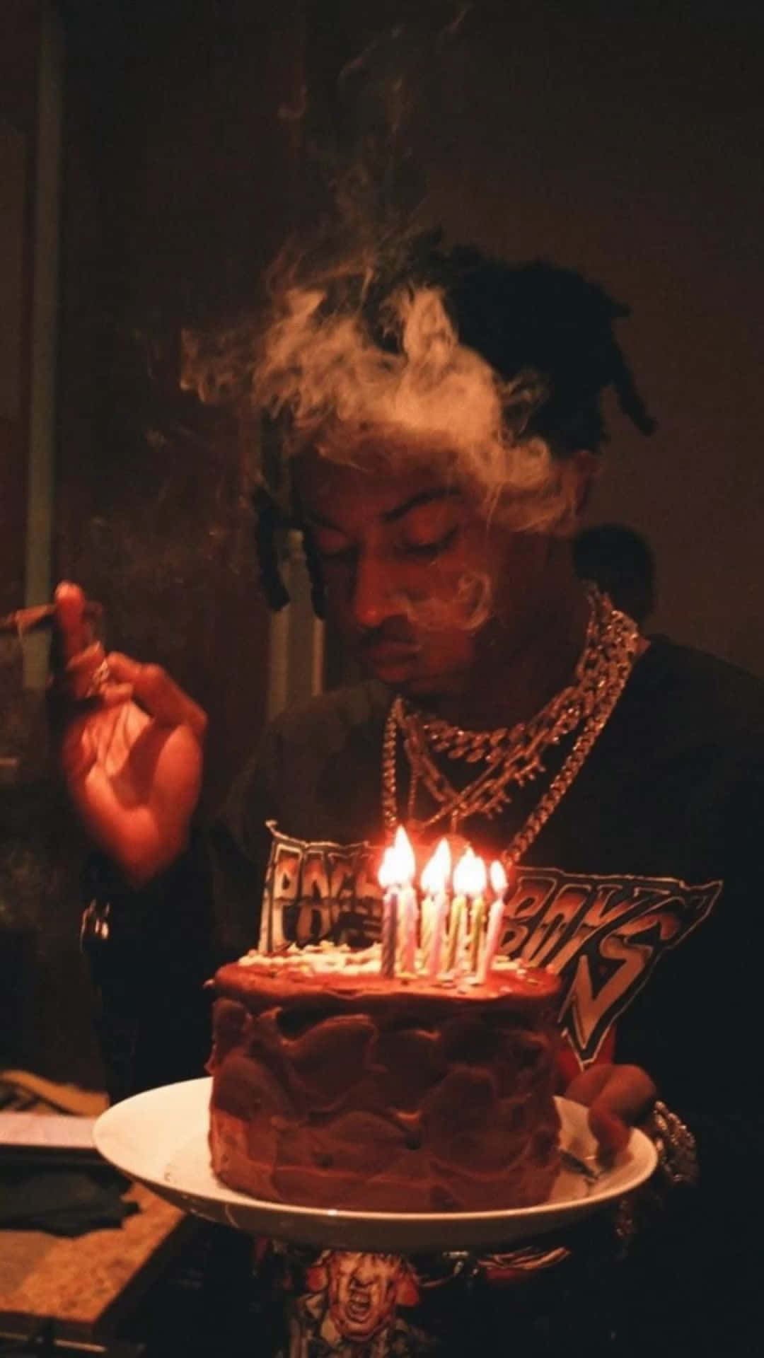 喺黑暗房間入面，喺點著蠟燭嘅生日蛋糕附近食煙嘅人。