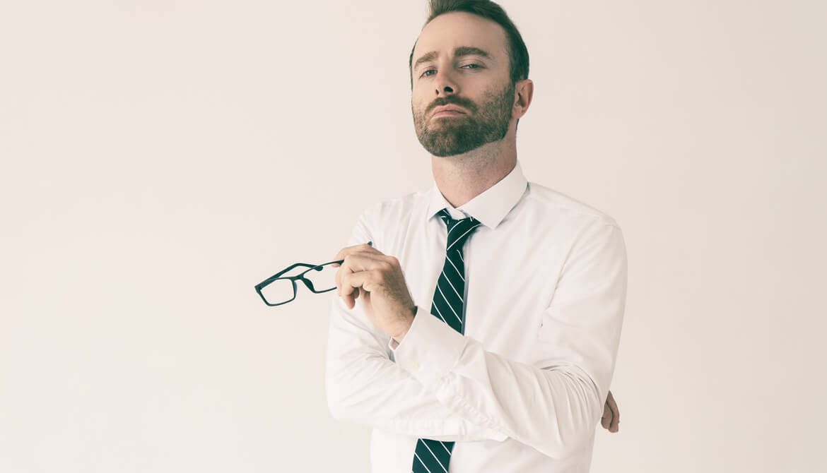 一個穿著商務服裝的男人，手持眼鏡，神情若有所思。