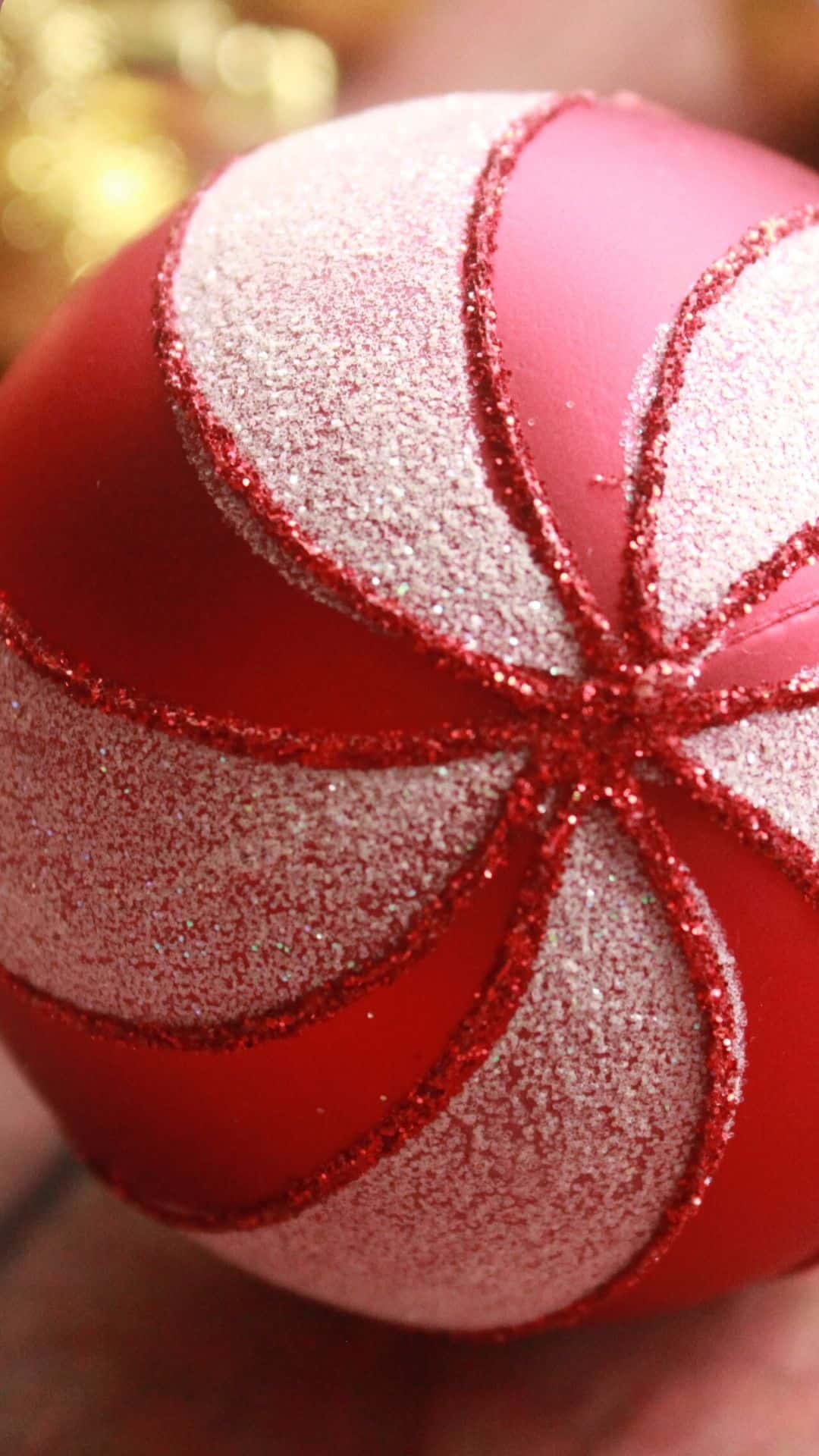 Red Aesthetic Christmas 桌布 壁紙 — 手持紅色和銀色閃亮聖誕裝飾品的特寫，帶有紅色閃粉邊緣。