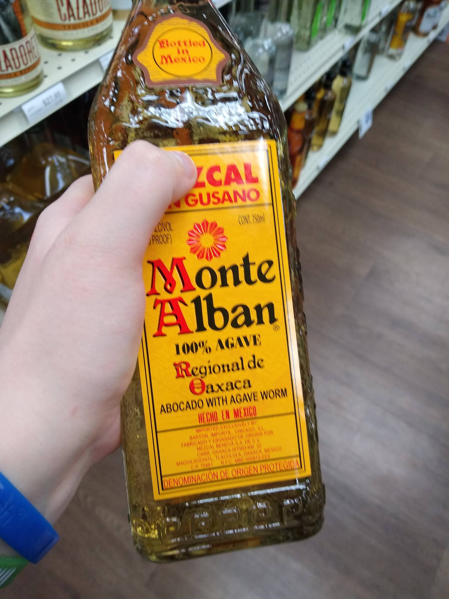 手在店內拿著一瓶Monte Alban龍舌蘭酒。