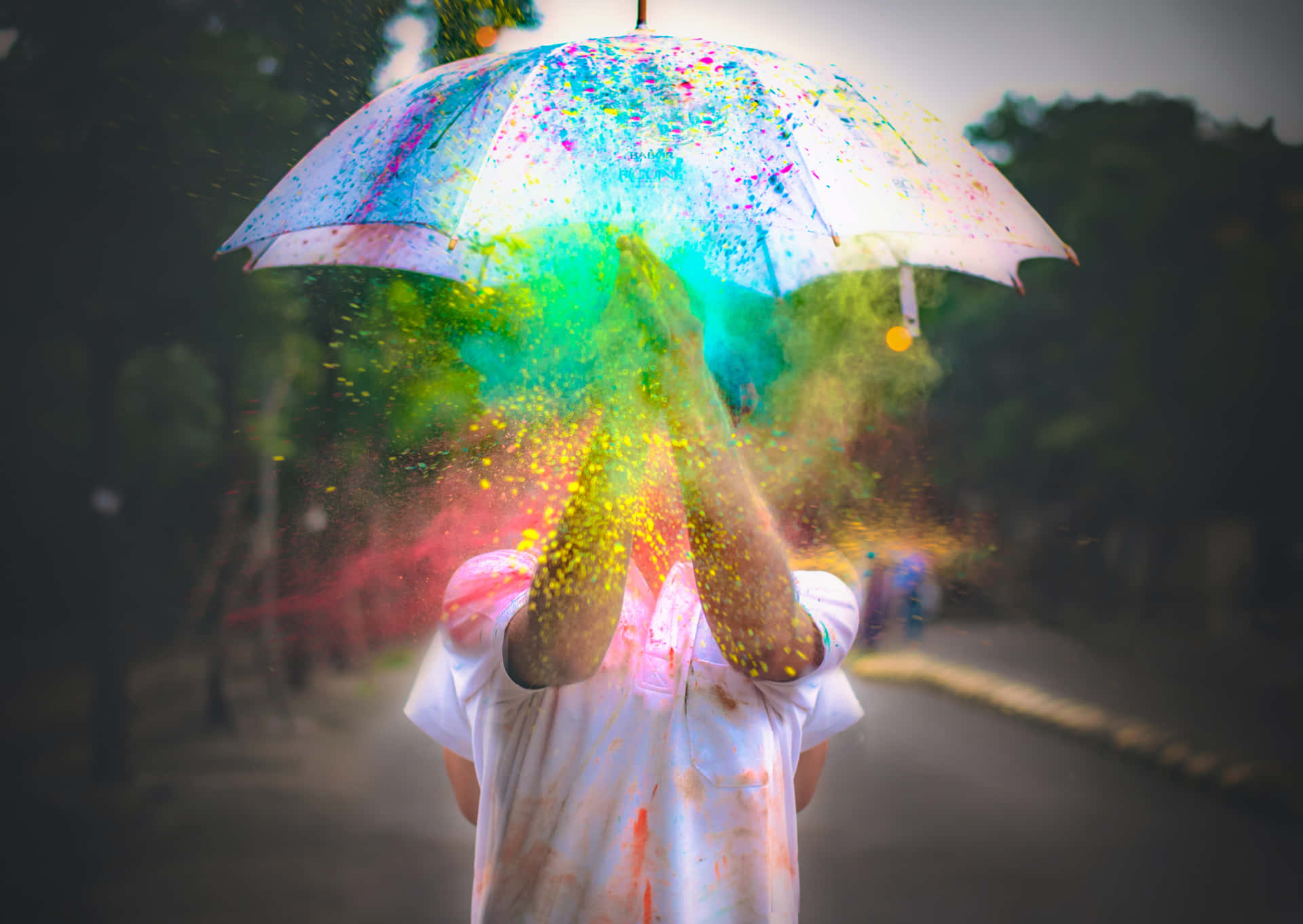 一個人在公園的雨傘下拋出彩色粉末。