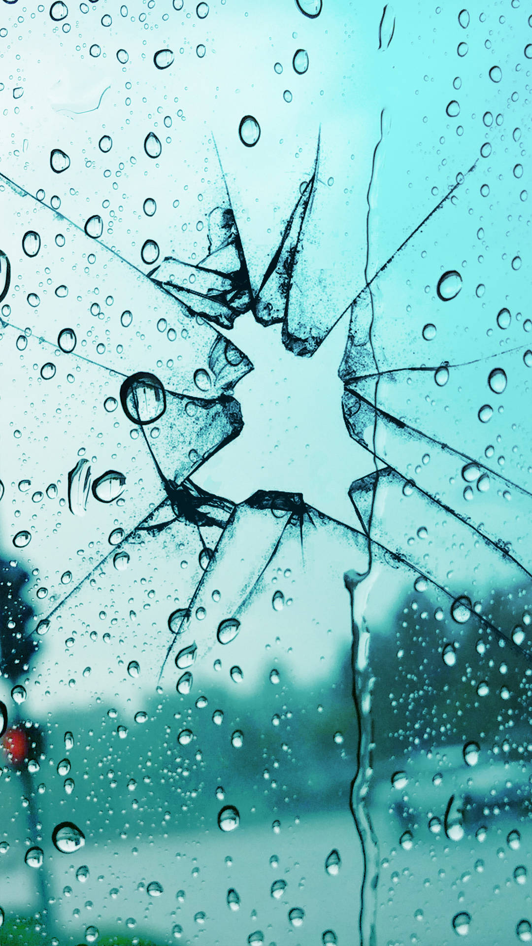 雨滴落在破裂的汽車擋風玻璃上，顯示模糊的藍色背景。