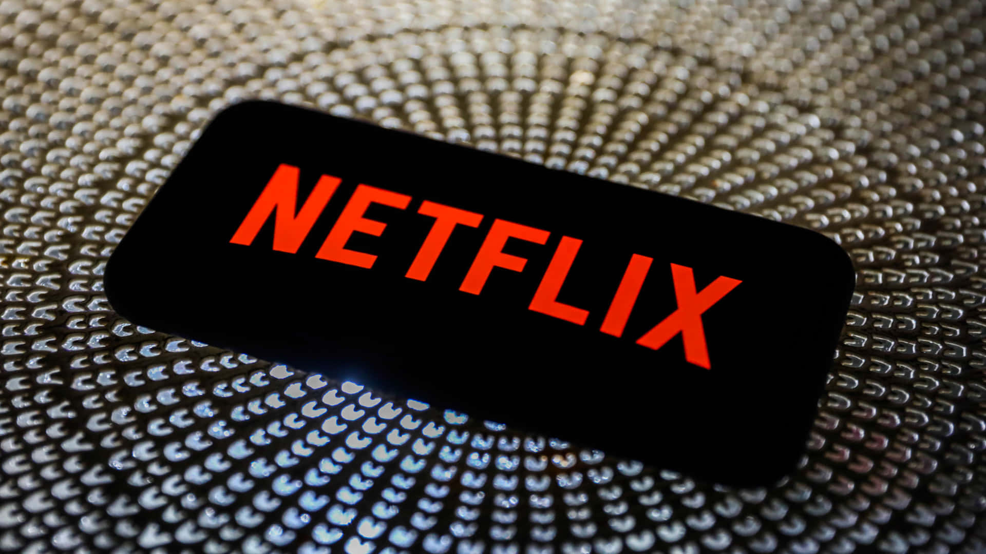 一部在金屬紋理背景上顯示Netflix標誌的智能手機。
