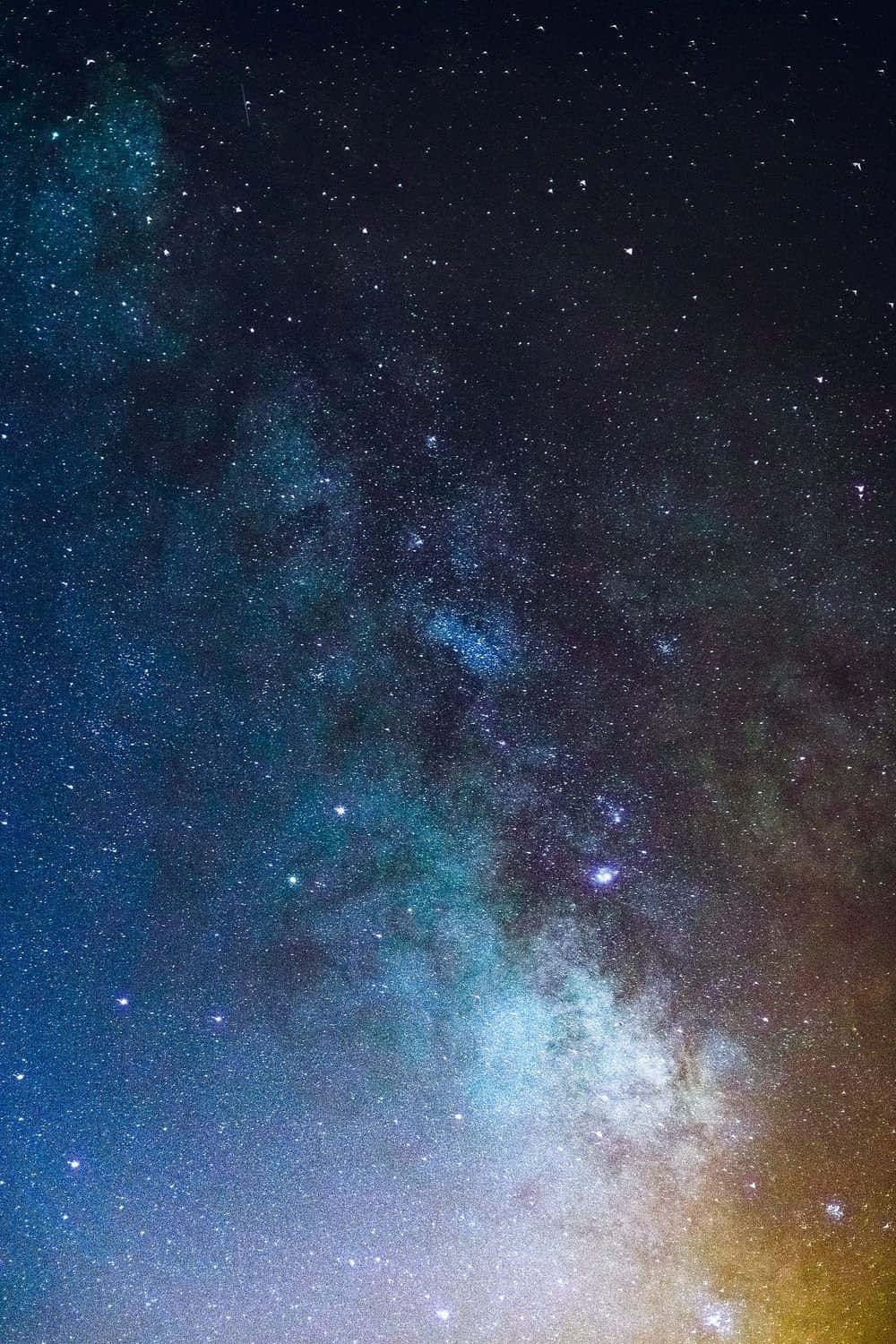 手機黑色夜空深空背景圖像 壁紙 — 令人驚嘆的銀河系景觀，在繁星點點的夜空下閃耀著鮮豔的藍色和金色。
