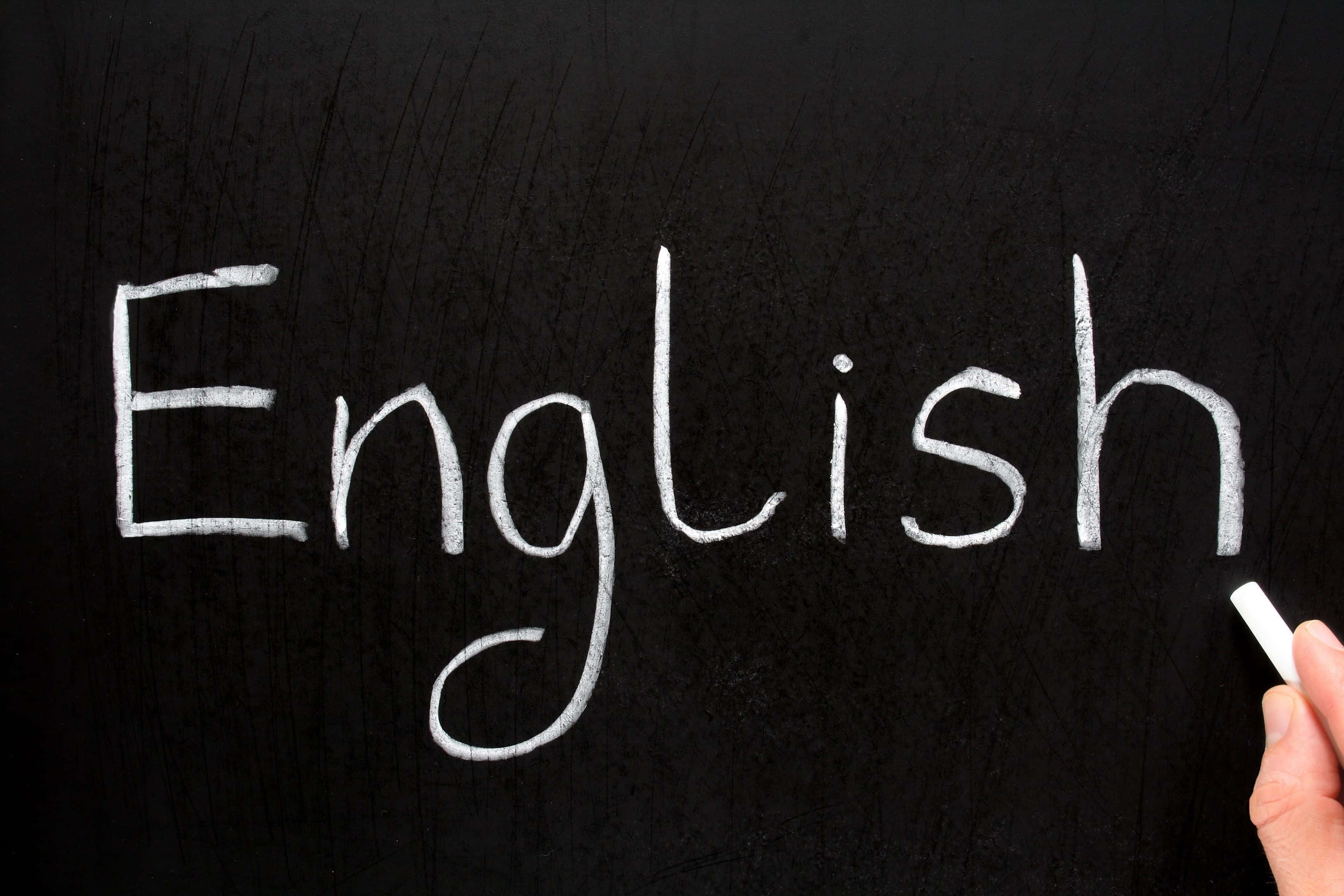 English 桌布 壁紙 — 手用白色粉筆在紋理黑板右邊寫上英文一詞，手握住粉筆。