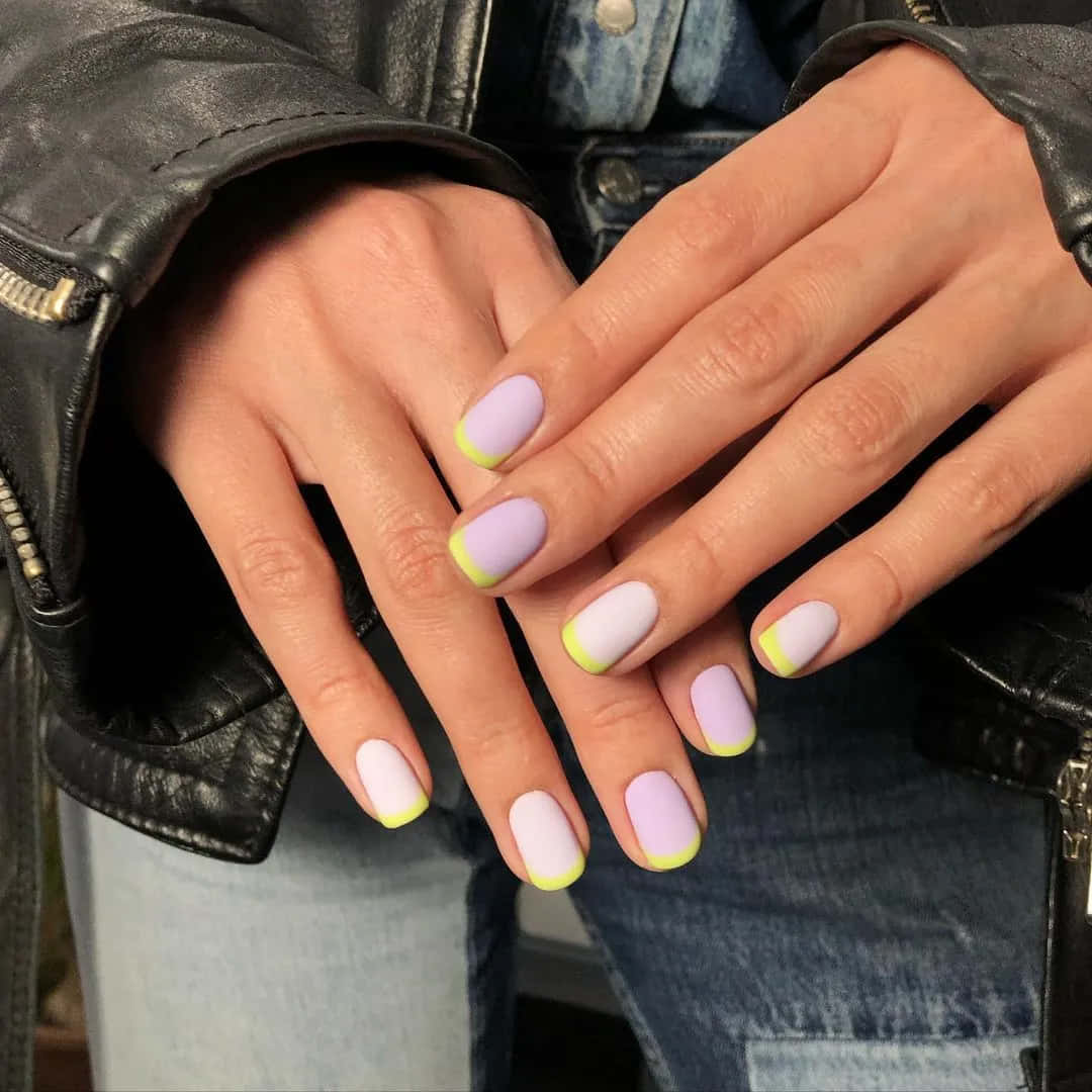 Spring Nails 桌布 壁紙 — 手部特寫，以黑色皮褸和牛仔布為背景，粉彩薰衣草色和白色指甲配上螢光黃色指尖。