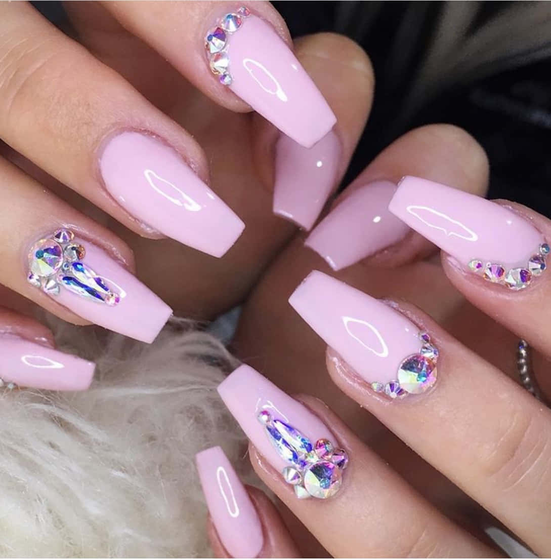 Pink Nails 桌布 壁紙 — 手部特寫，帶有光澤的淺粉紅色棺材指甲，飾有彩虹色水鑽和白色橢圓形貼花。