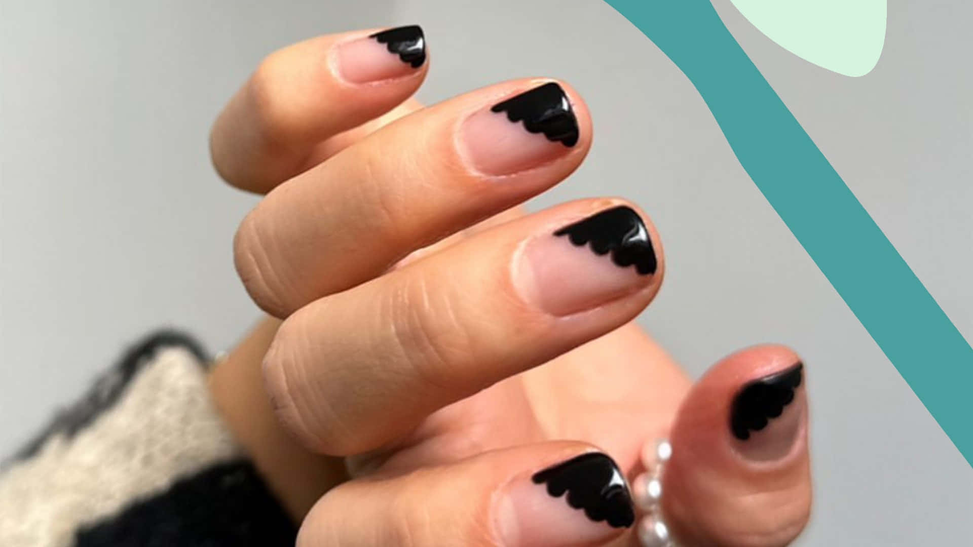 Halloween Nail Art 桌布 壁紙 — 手部特寫，帶有別緻的黑色扇貝形指甲藝術，背景為柔和的灰色和藍綠色。