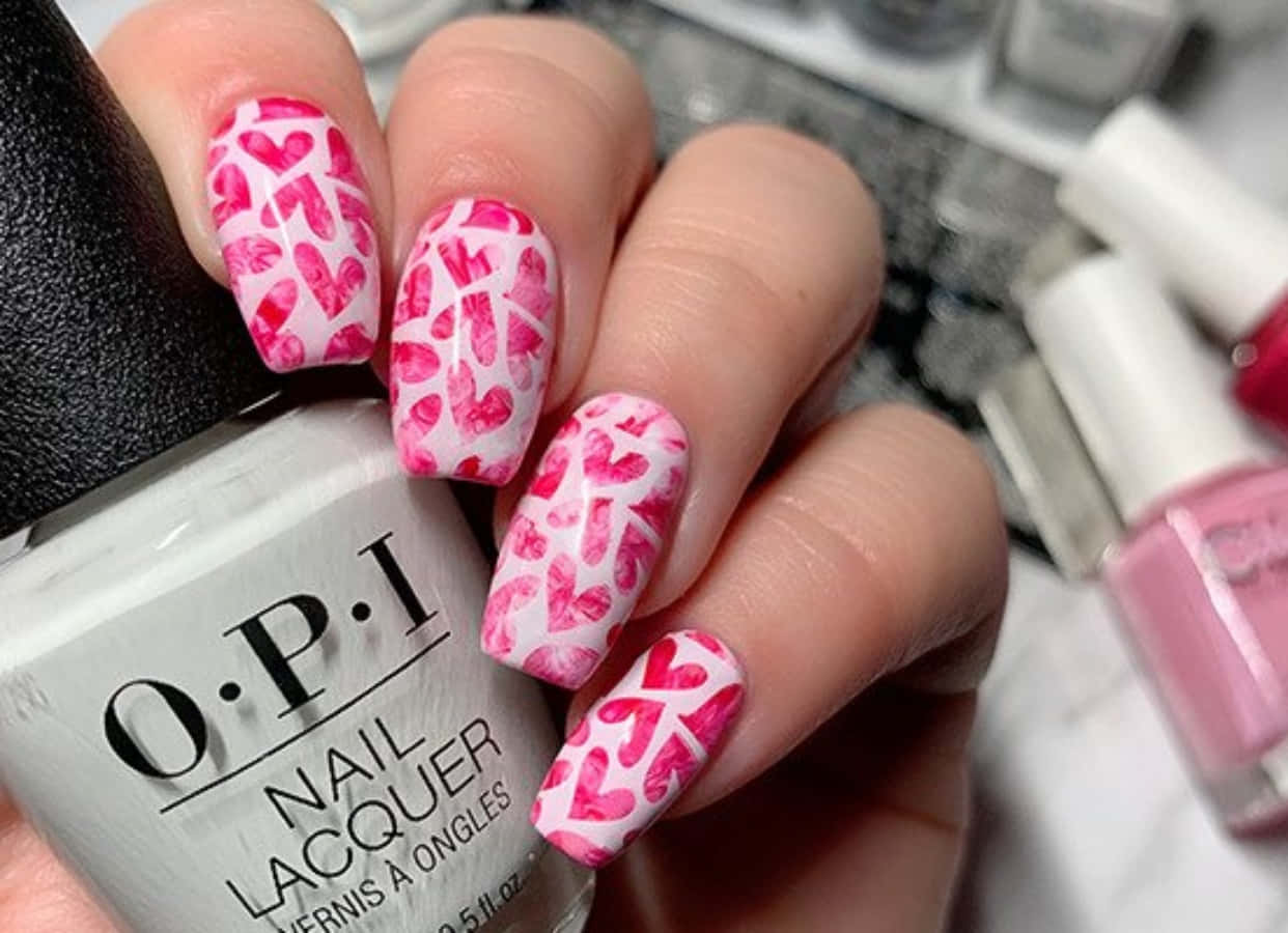 Pink Nail Art 桌布 壁紙 — 手部特寫，白色指甲上飾有粉紅色心形圖案，握著一支OPI指甲油瓶。