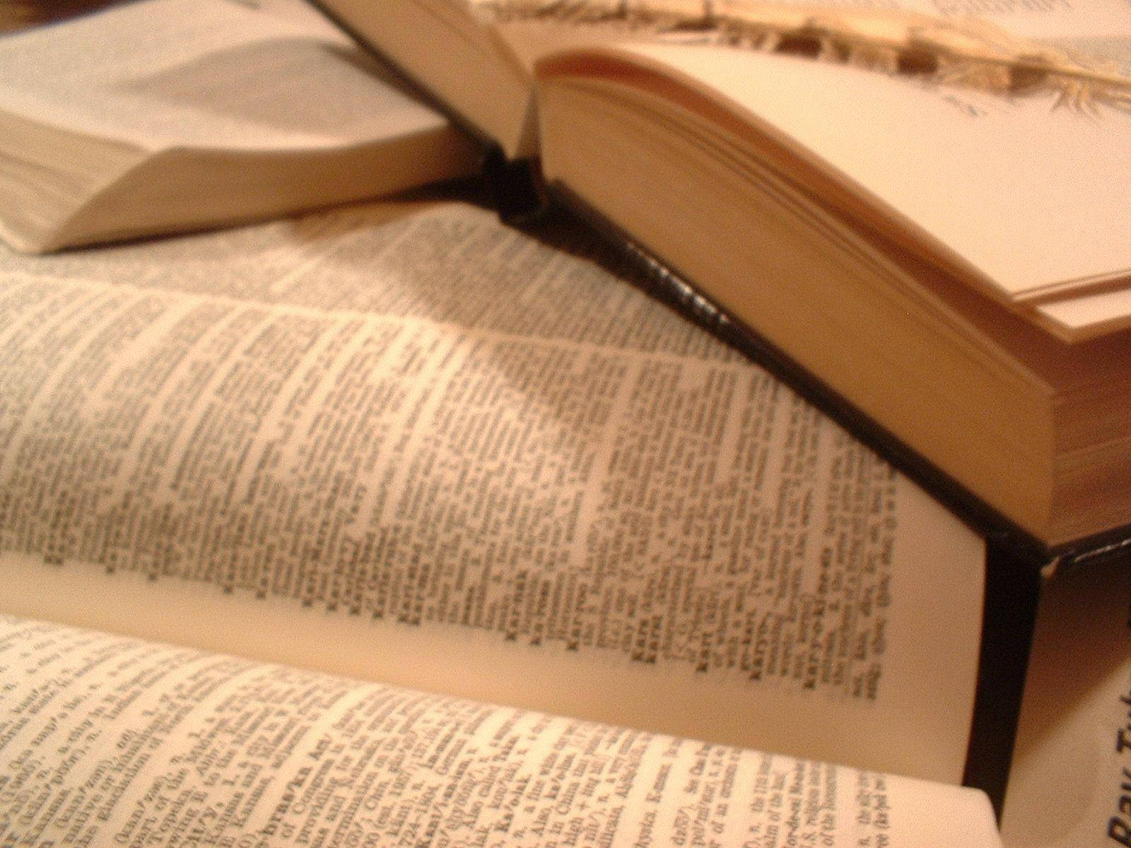 打開的厚重字典書 壁紙 — 打開的復古書籍特寫，書頁泛黃，黑色書脊，放在木質表面上。