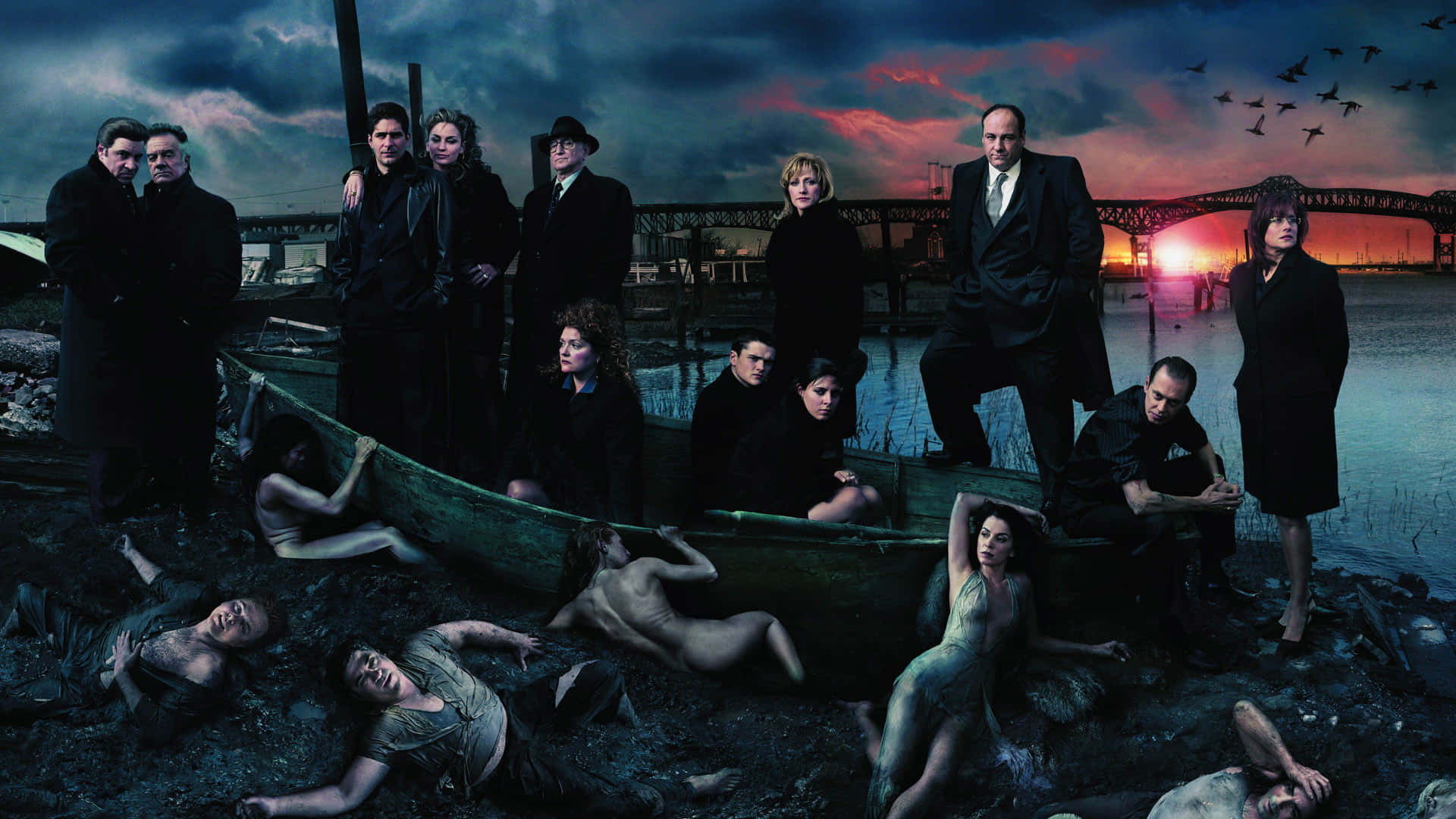 日落時分，一群身穿深色西裝、裸露身體的演員在海濱圍繞一艘船擺姿勢。