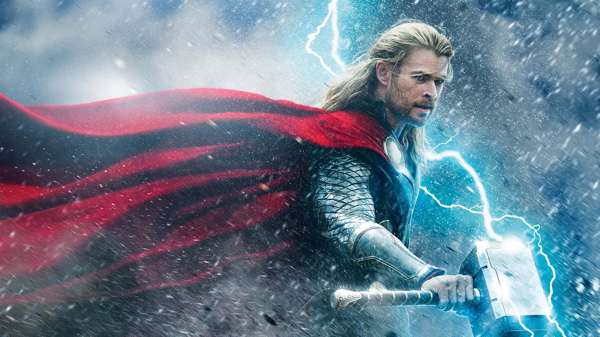 God Of Thunder 桌布 壁紙 — 托爾在暴風雨的天空下揮舞著發光的錘子，紅色斗篷戲劇性地飄揚。
