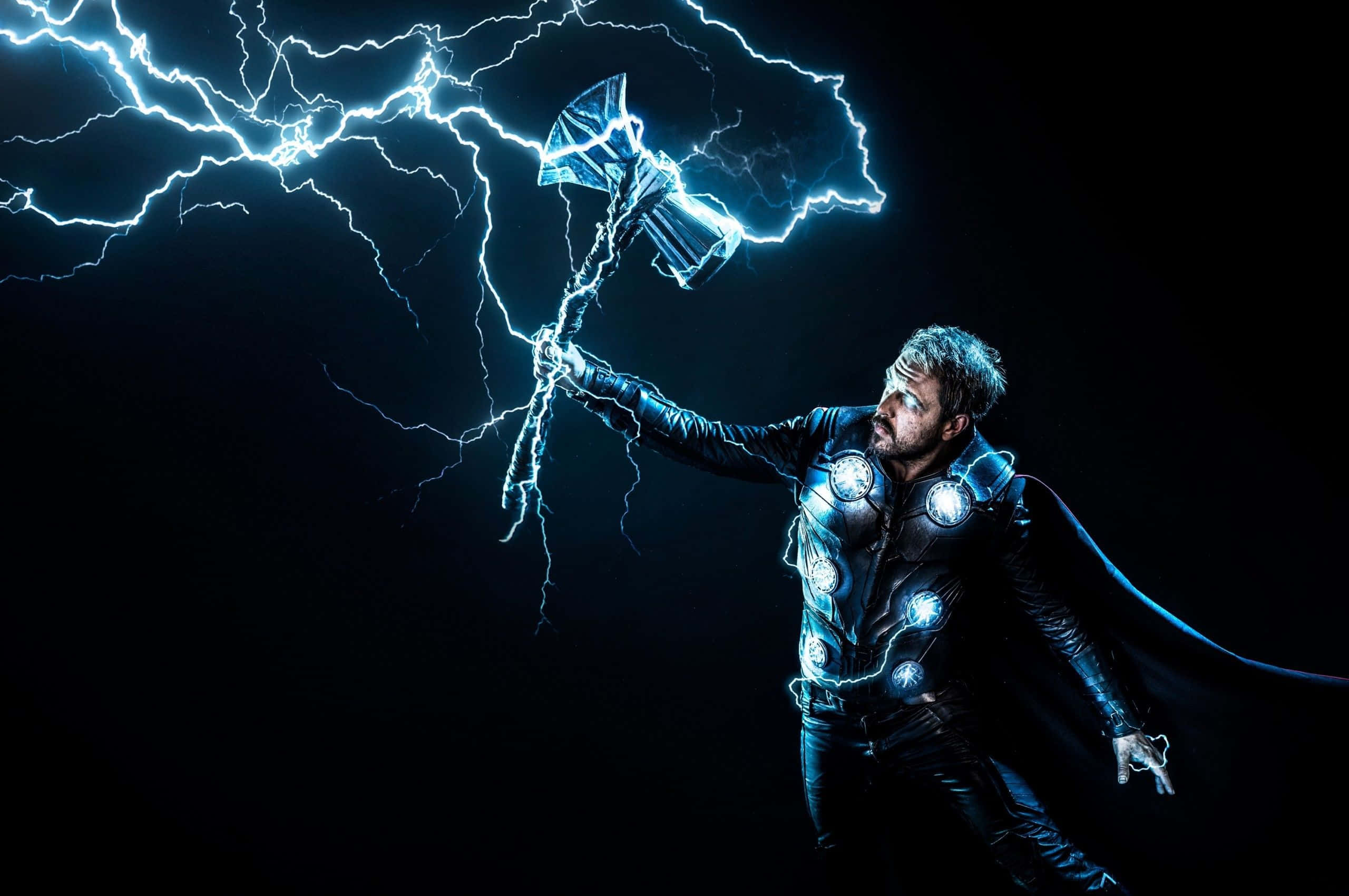 God Of Thunder 桌布 壁紙 — 托爾揮舞著發光的錘子，電光在他周圍的黑暗虛空中噼啪作響。