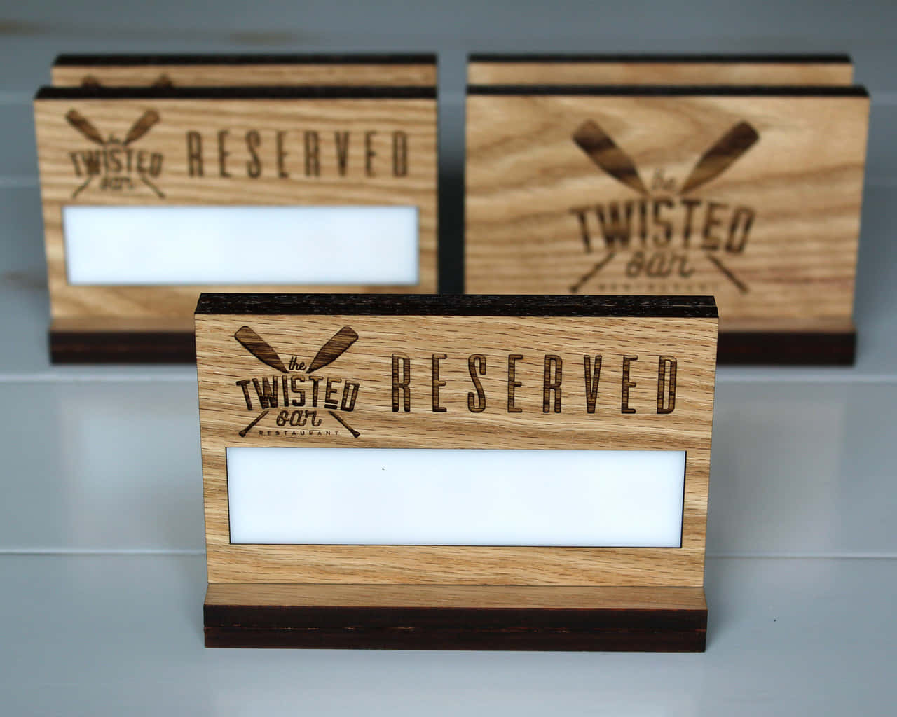 灰色檯面上的 Twisted Bar Restaurant 三個木製預訂牌。