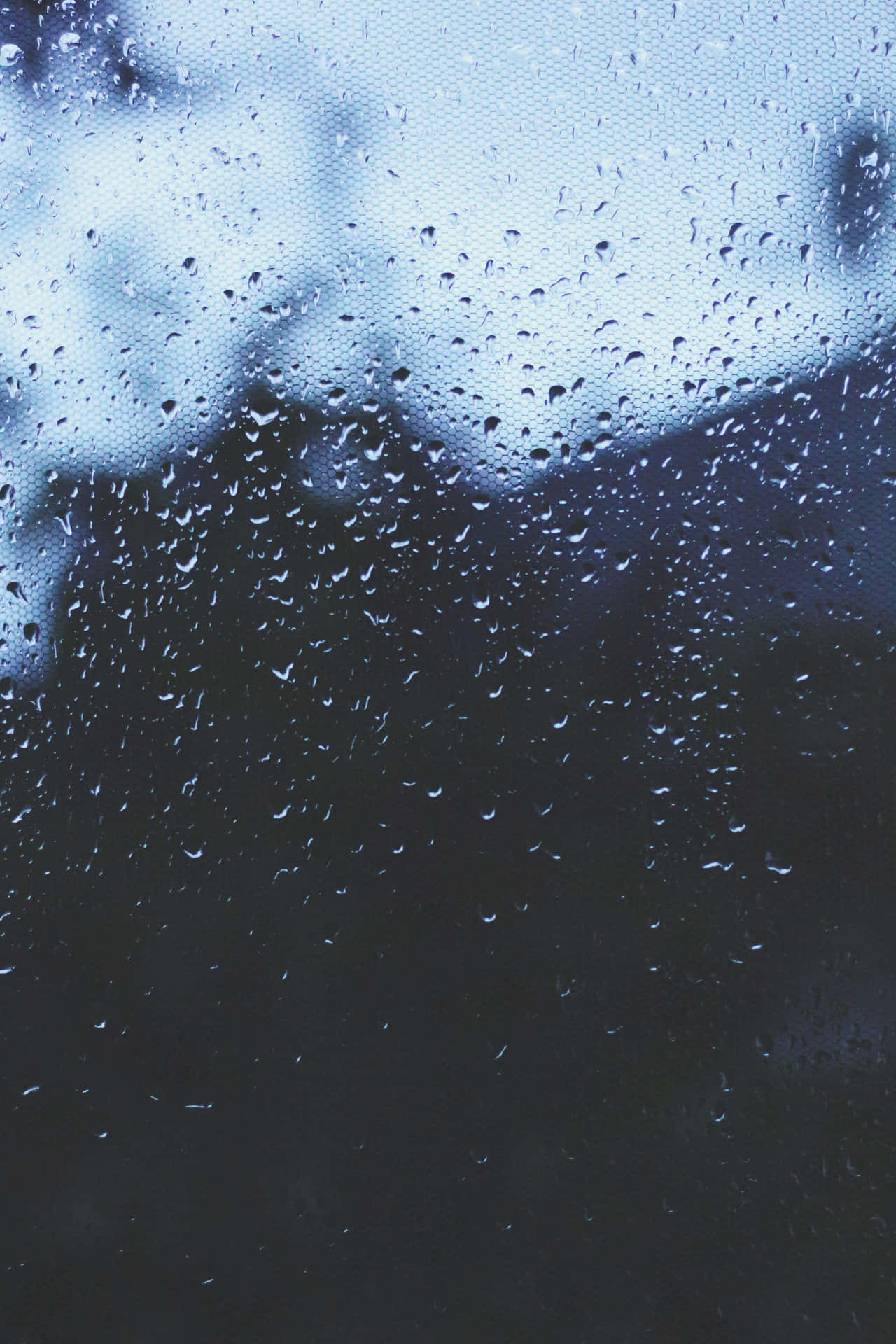 玻璃上的雨滴遮擋了黑暗的戶外場景。