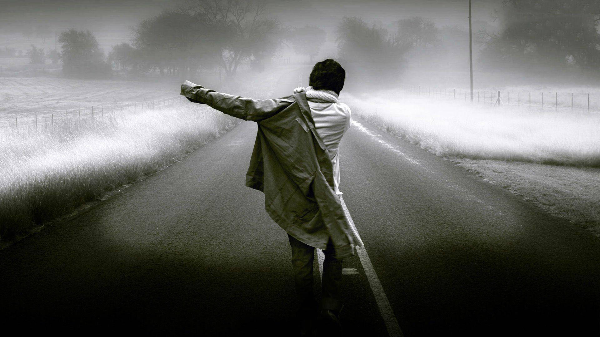 一個人站在霧氣瀰漫的路上，穿著外套，雙臂張開。