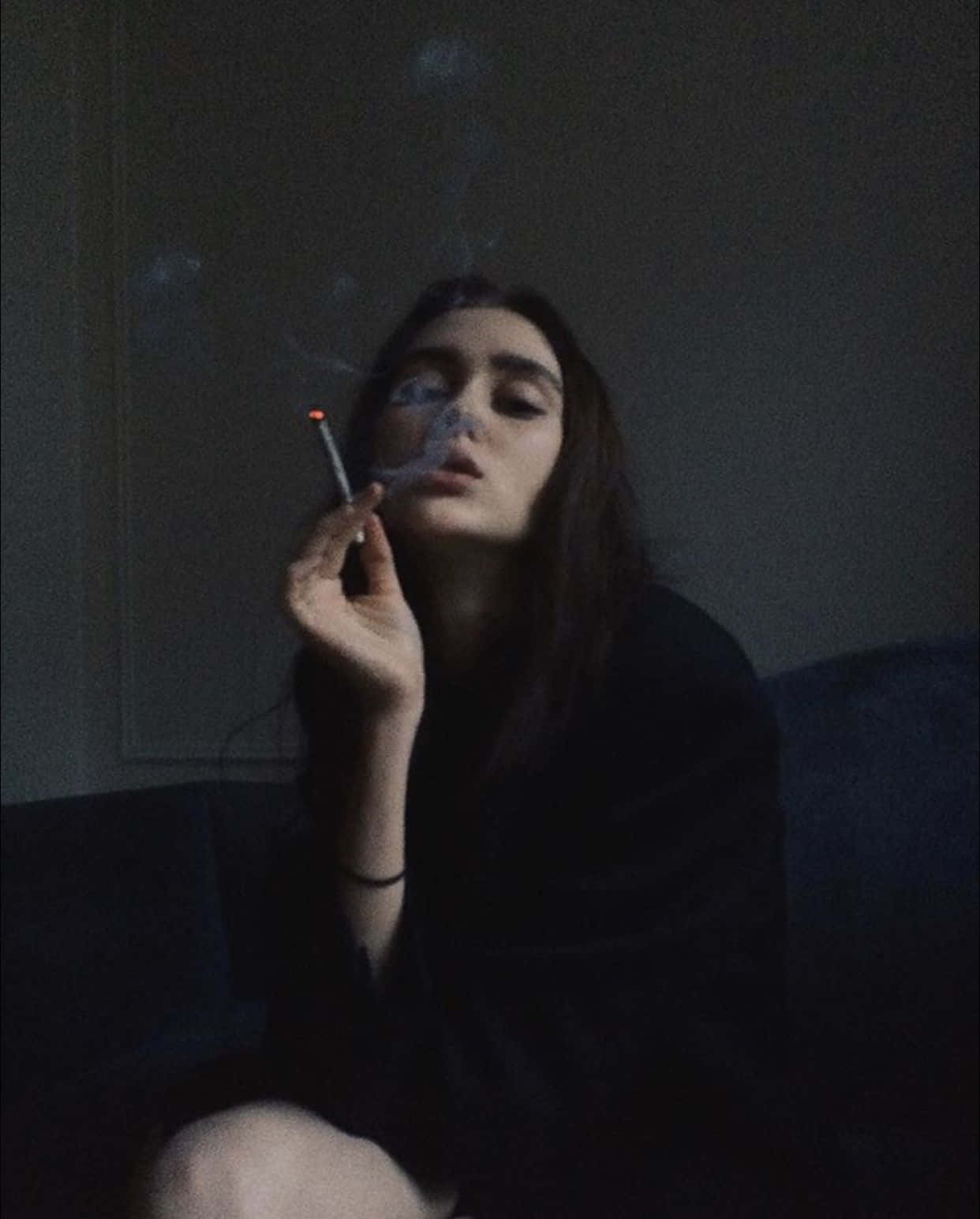 一位女士在室內昏暗燈光下抽煙，煙霧在她臉龐旋轉。