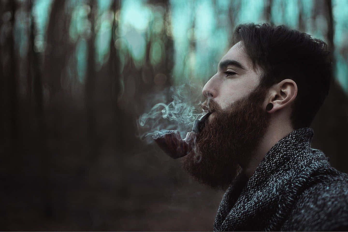 鬍鬚男人在森林中用青色燈光吸煙斗