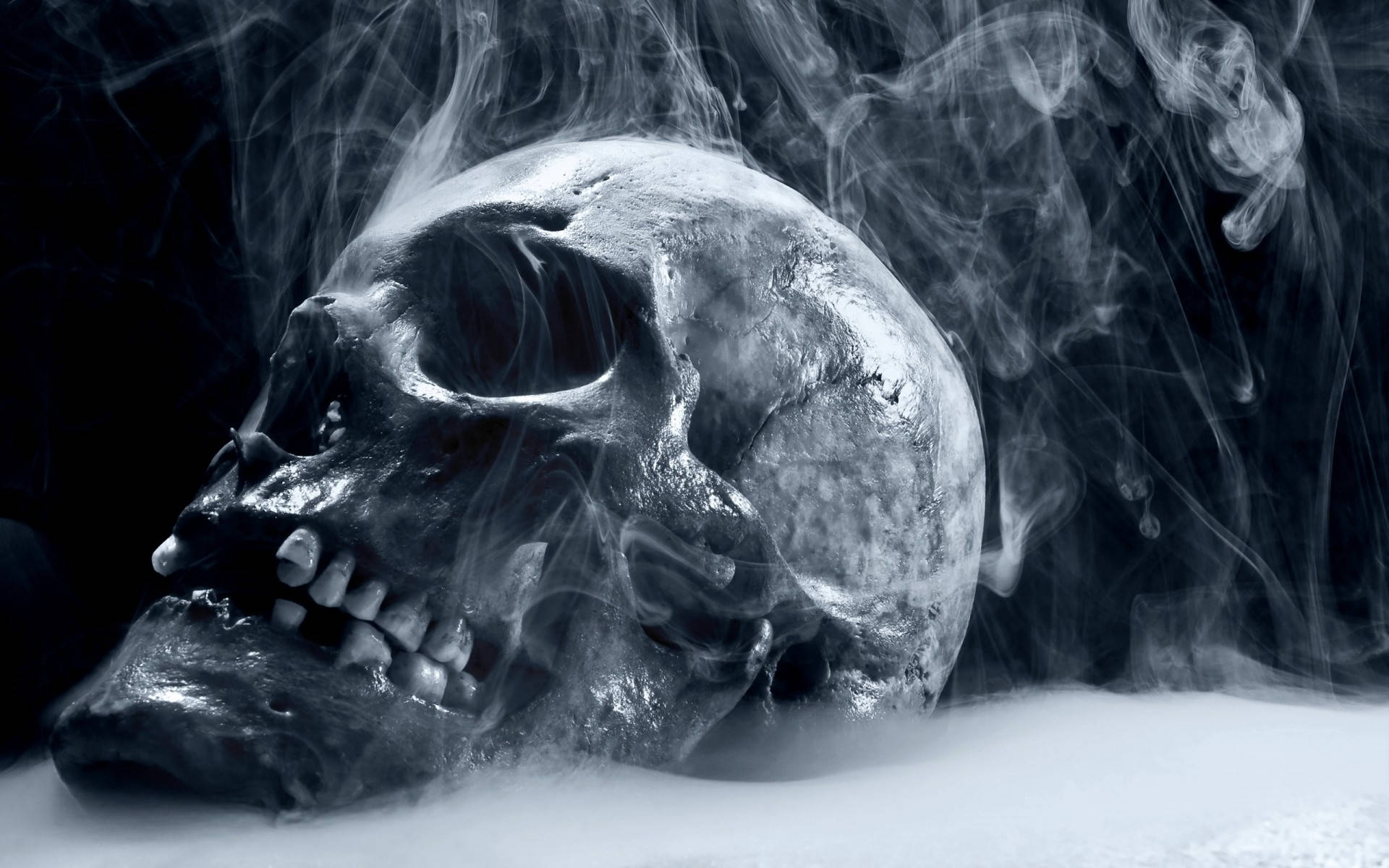 抽菸高清骷髏 壁紙 — 一個令人毛骨悚然的人類頭骨從黑暗背景中旋轉的煙霧中浮現，空洞的眼睛以詭異的靜止凝視著。