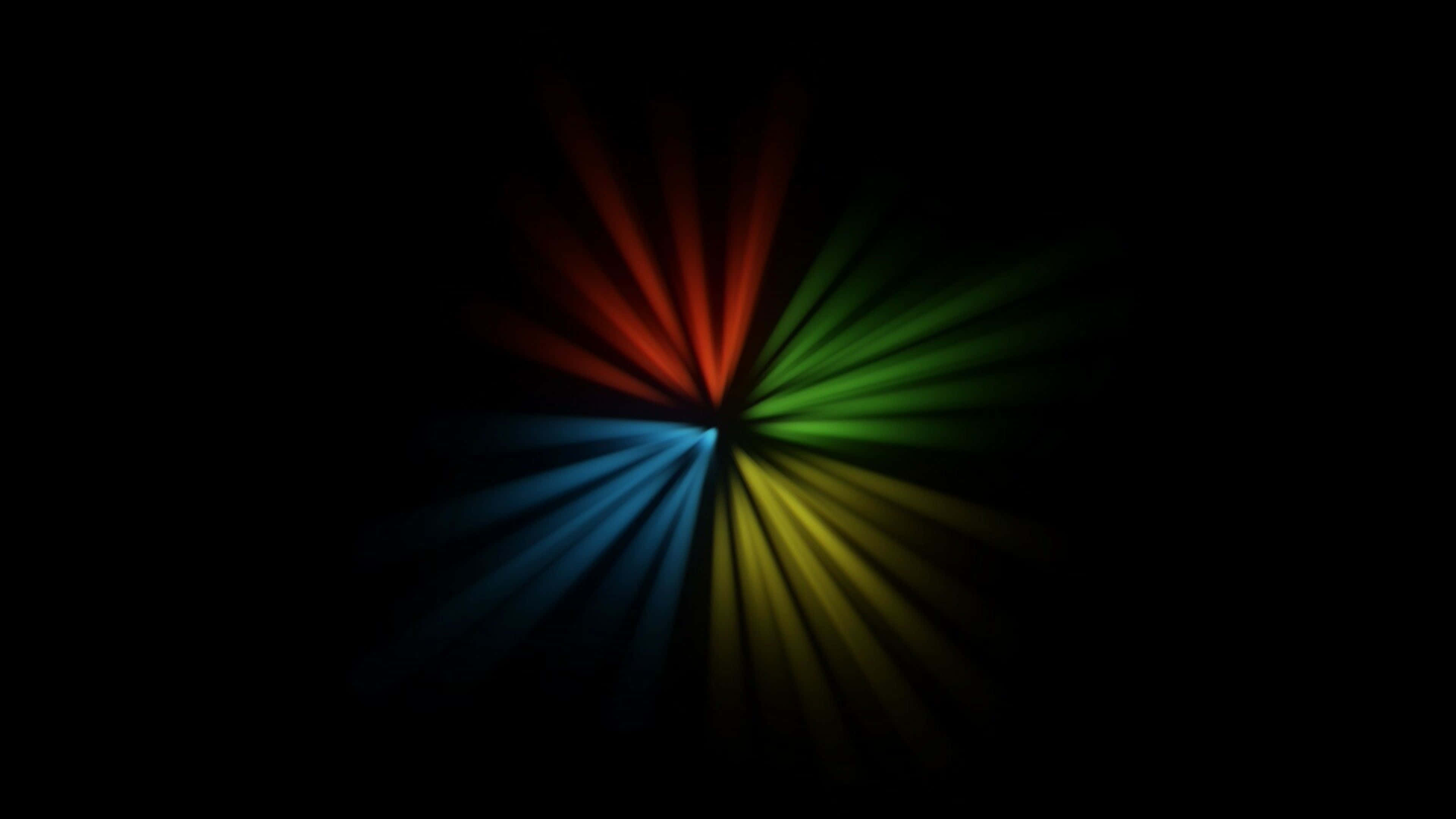 抽象 Windows 標誌 AMOLED 桌面 壁紙 — 鮮豔的雷射光束從中心點向漆黑背景放射，形成紅、綠、藍、黃的對稱爆發。