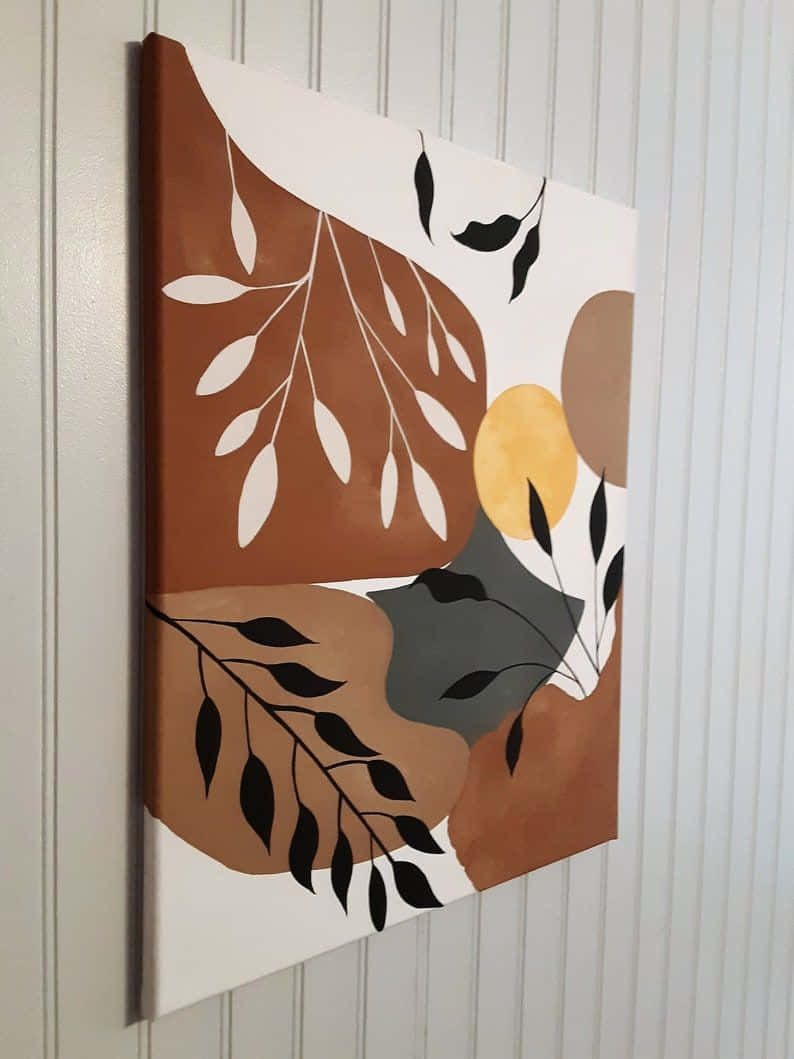 Minimalist Painting 桌布 壁紙 — 抽象現代帆布藝術，以大地色調的風格化葉子裝飾，掛在白色鑲板牆上。