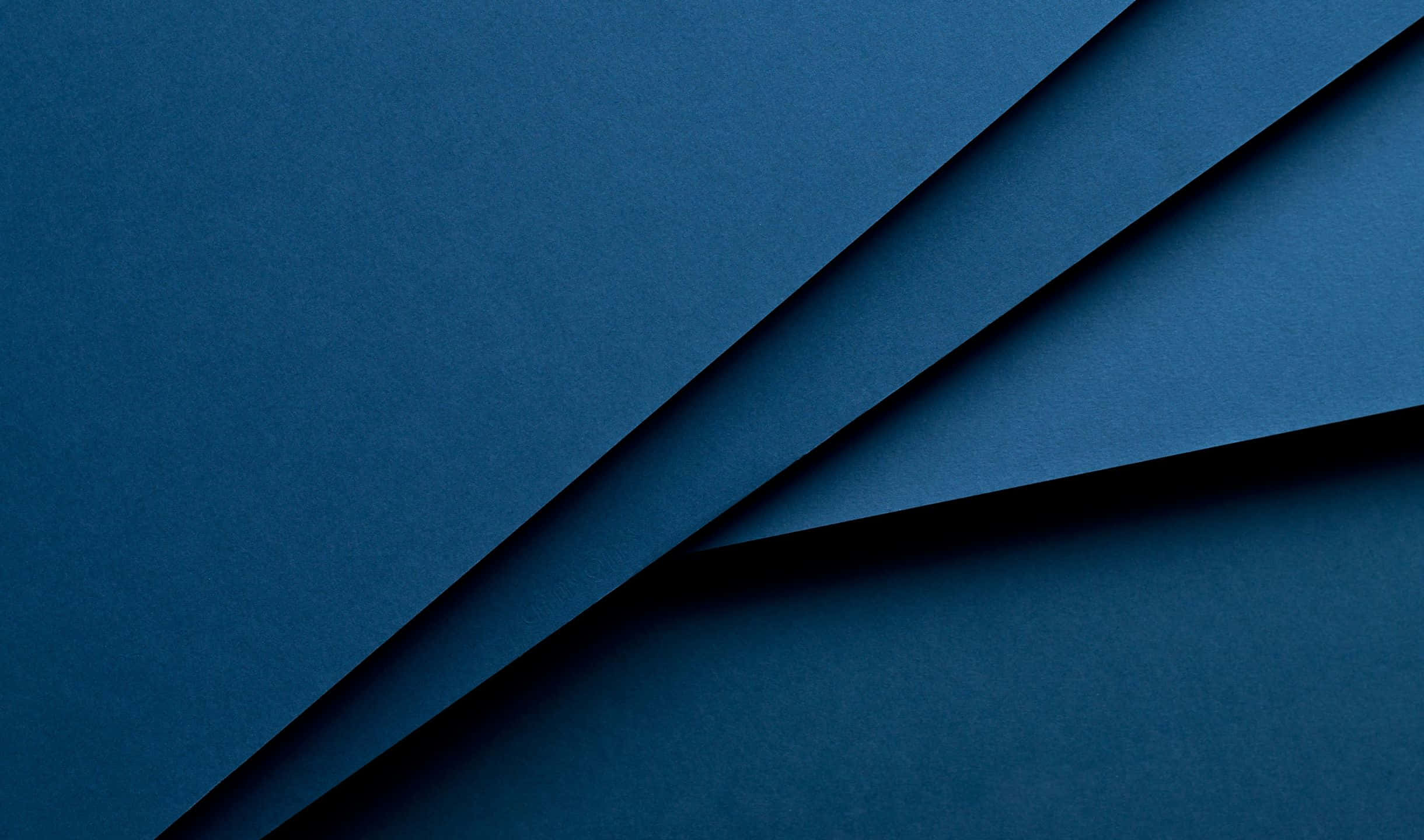 抽象紋理 2440x1440 材質壁紙 壁紙 — 深藍色紋理紙張摺疊營造出極簡抽象構圖，帶有柔和陰影和乾淨線條。