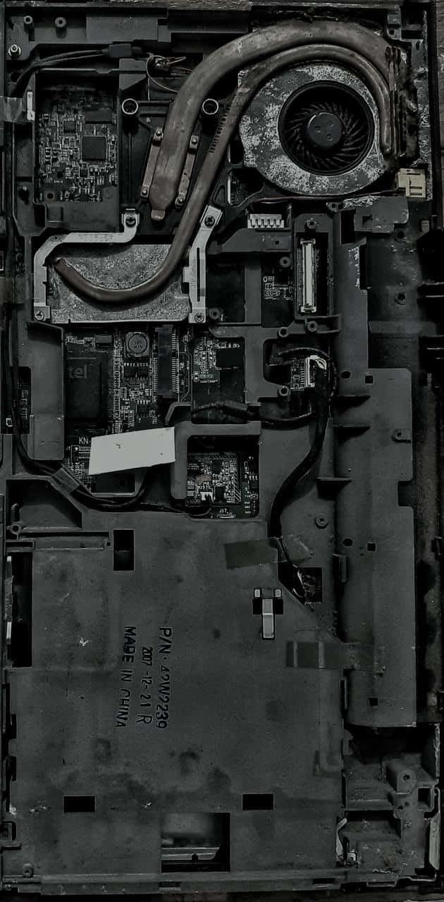 Motherboard 桌布 壁紙 — 拆解筆記型電腦內部的單色特寫，顯示佈滿灰塵的電路板和磨損的散熱風扇。