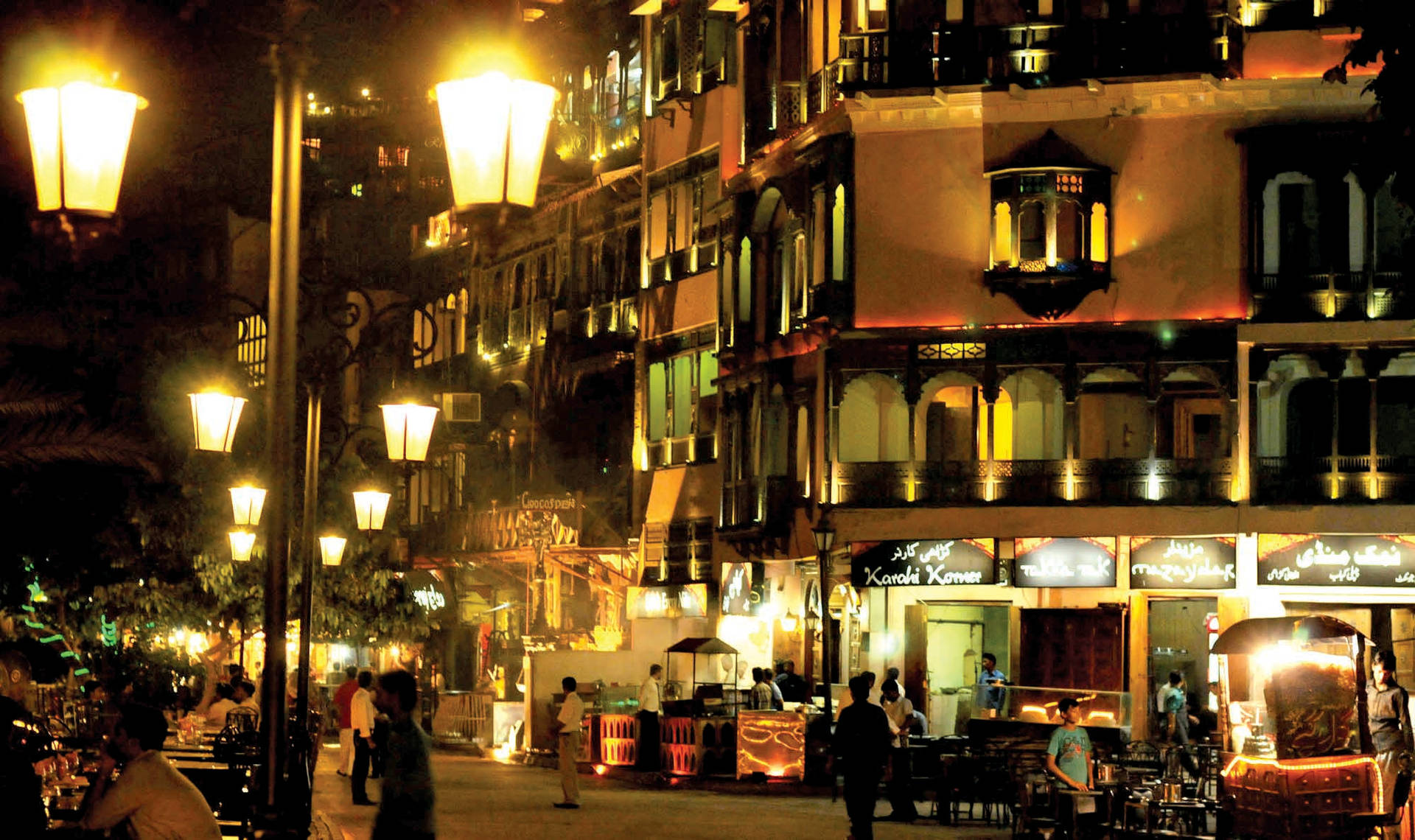 夜晚街道，燈光閃爍，人們走過明亮的建築。