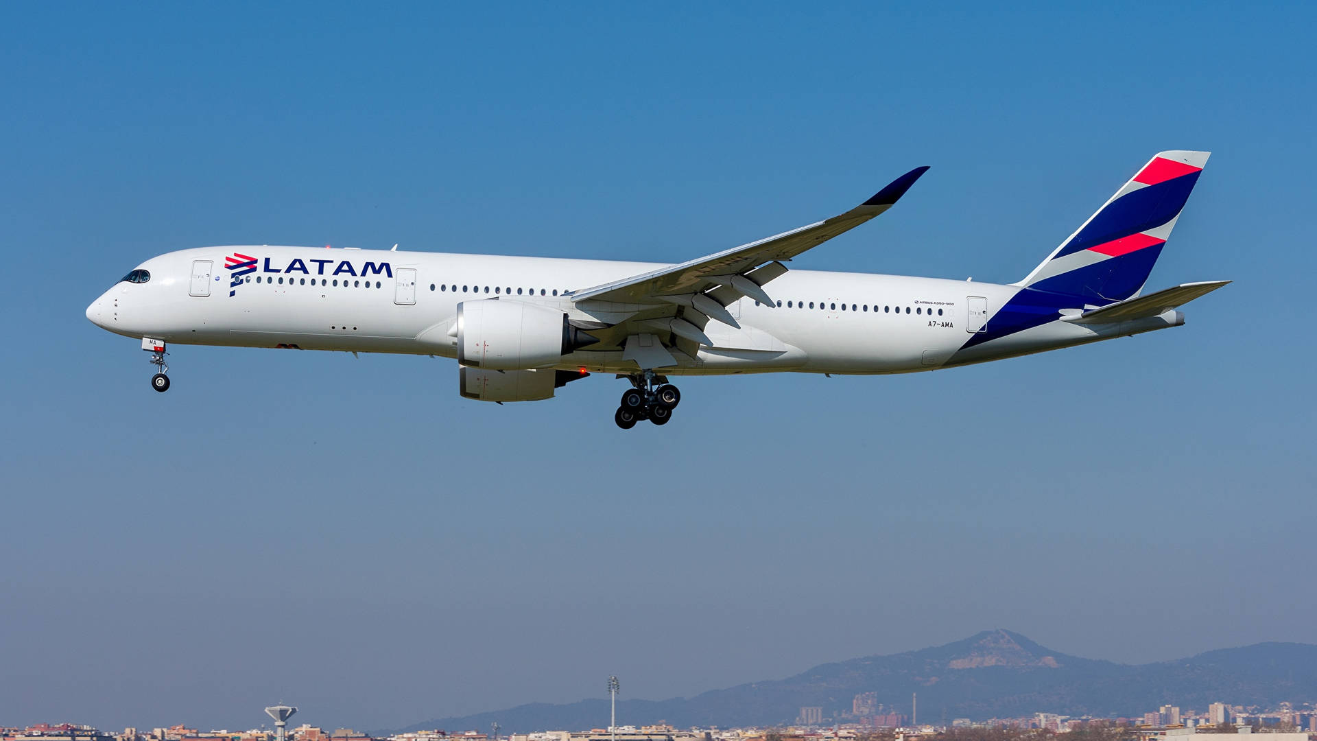 LATAM飛機以山脈和城市為背景降落