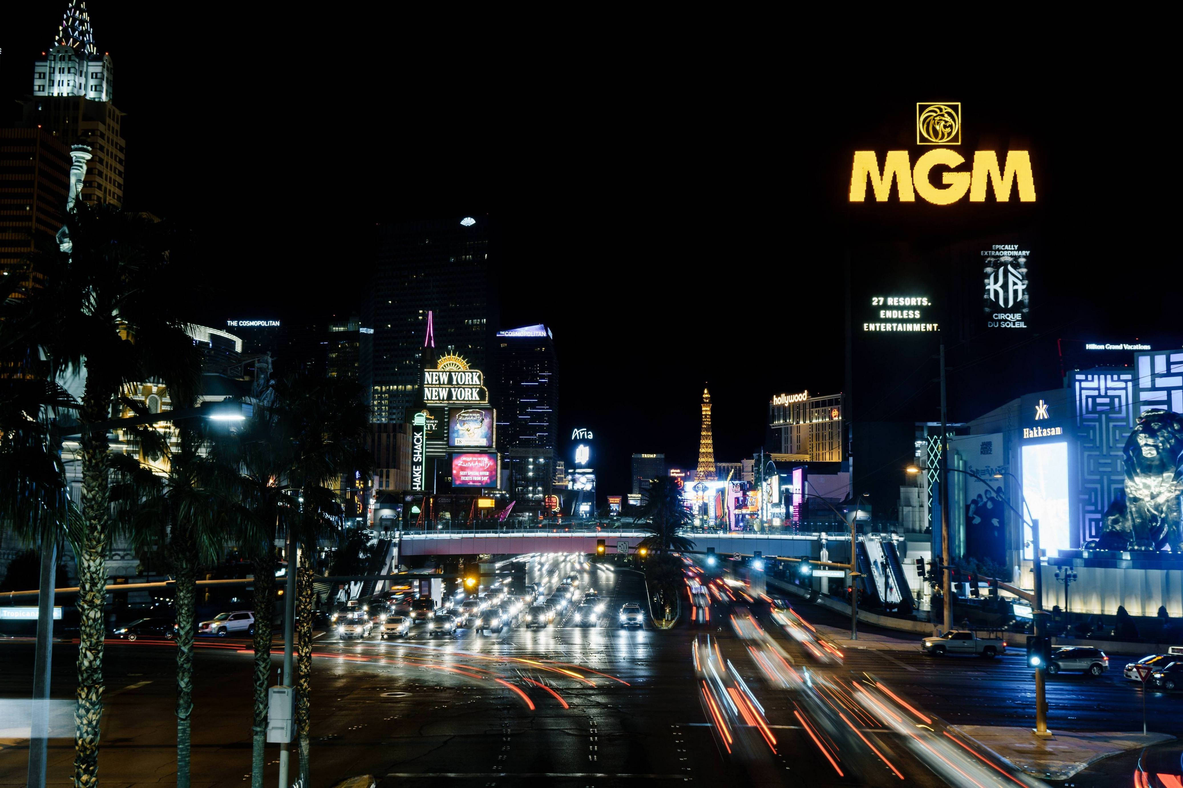 拉斯維加斯 4K MGM 大酒店 壁紙 — 充滿活力的霓虹燈照亮了夜晚繁忙的拉斯維加斯大道，伴隨著流動的車燈和高聳的賭場招牌。