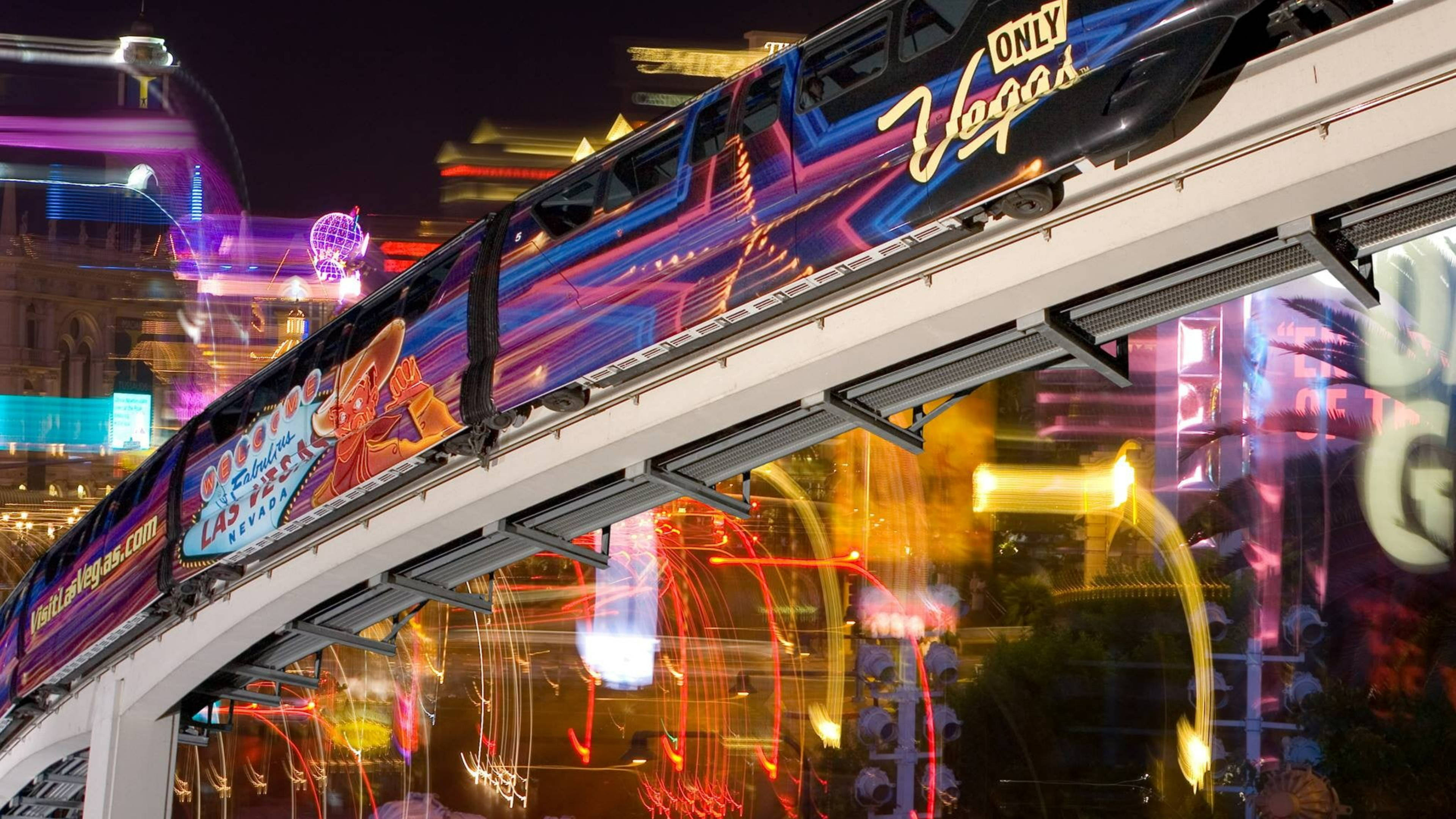 拉斯維加斯單軌電車 壁紙 — 一列標有「ONLY Vegas」的單軌列車在燈火輝煌的拉斯維加斯大道上滑行，伴隨著色彩繽紛的霓虹燈條紋，充滿活力的夜景。