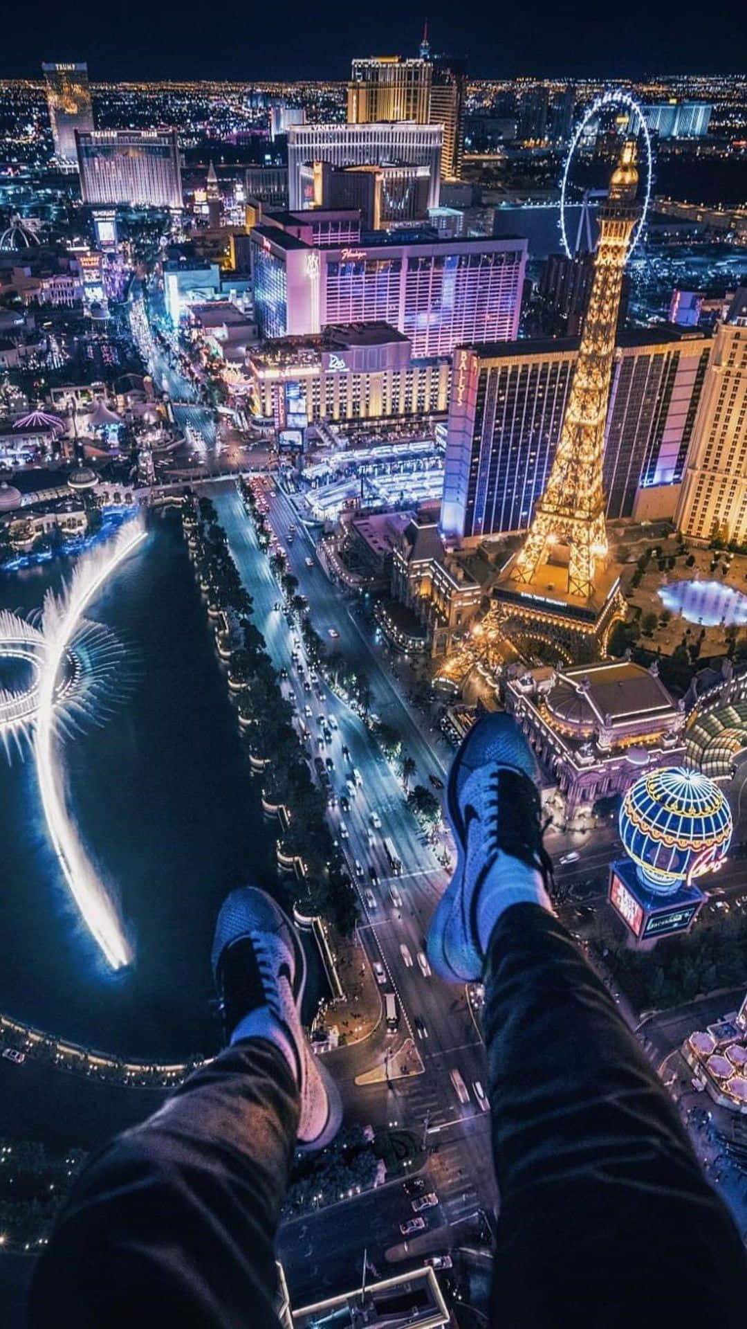 穿著運動鞋的雙腳懸掛在夜晚拉斯維加斯的城市燈光之上。