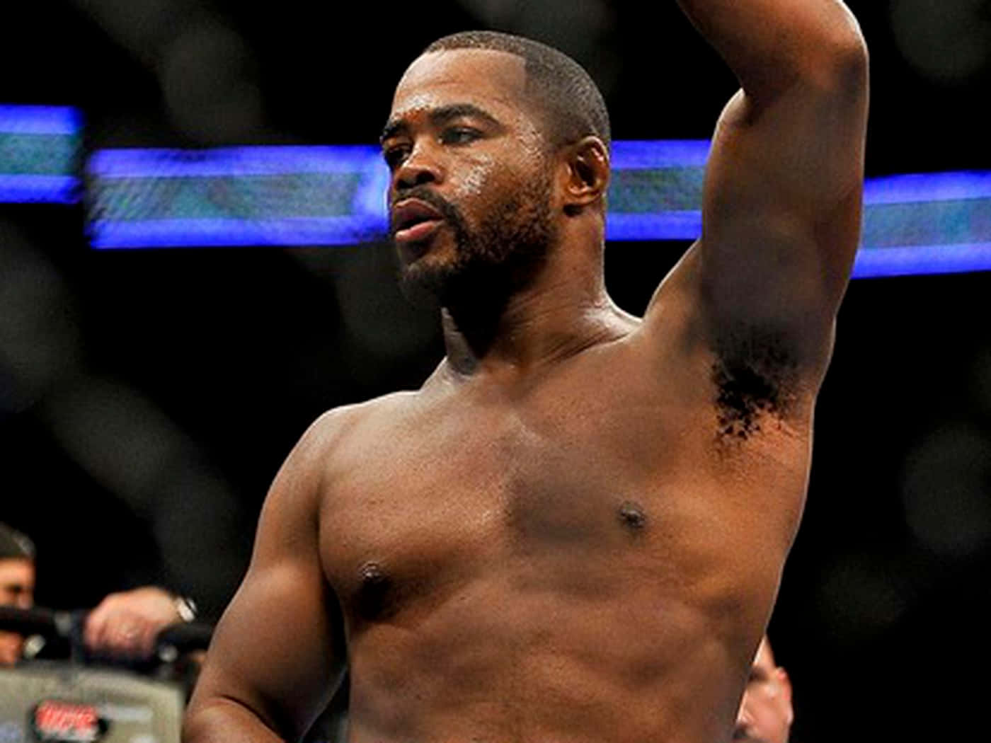 一位赤裸上身的MMA鬥士在明亮的八角籠中勝利地舉起手臂。