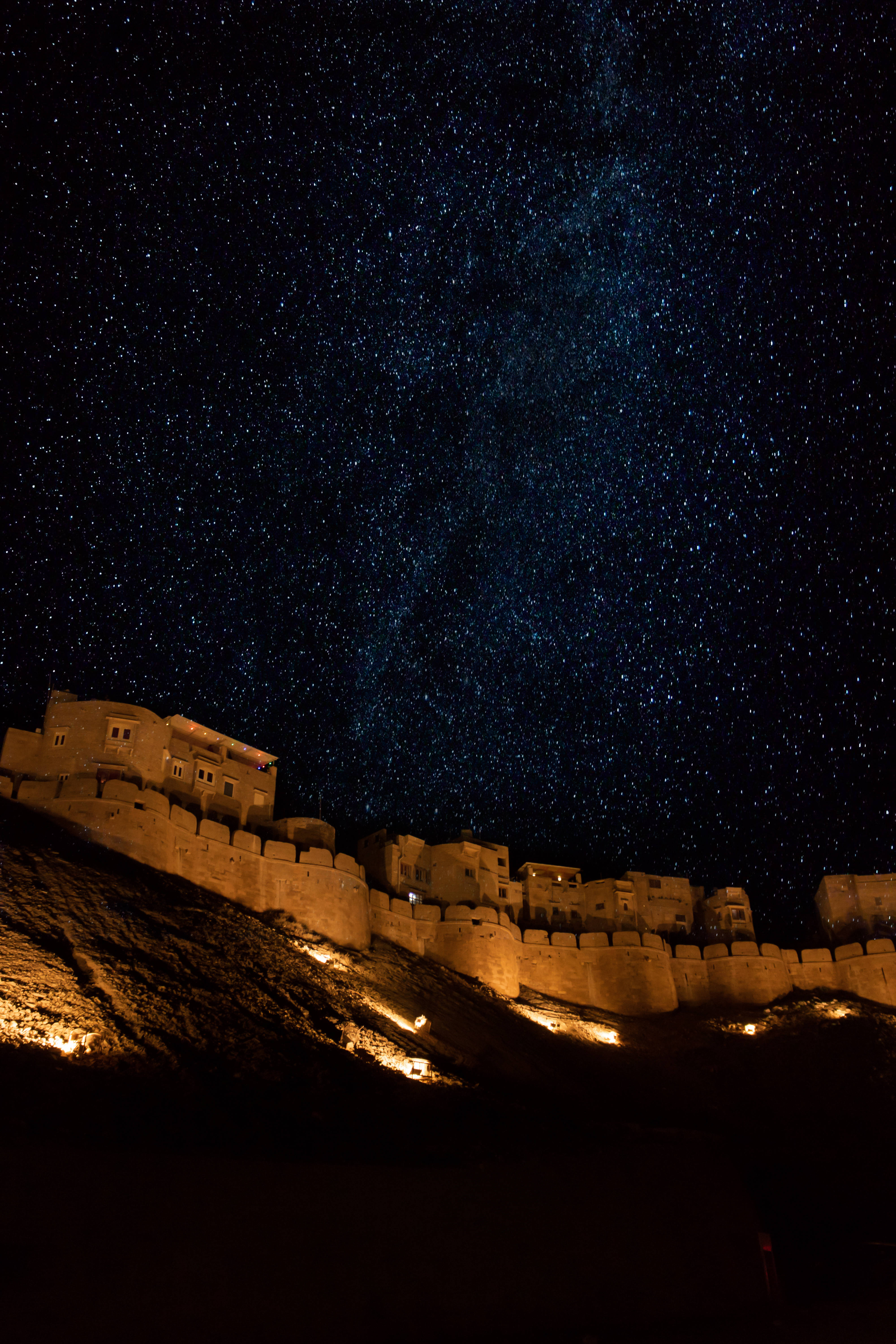 拉賈斯坦金城傑薩爾默堡的美麗夜景 壁紙 — 古老石堡在夜晚被照亮，下方是令人驚嘆的星空，銀河清晰可見。