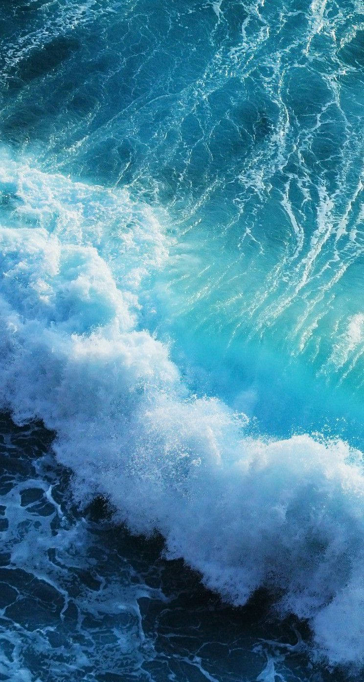 拍岸海浪 iPhone 活動壁紙 壁紙 — 強勁的海浪拍打著深藍色的海水，激起泡沫般的白色浪花，呈現動態特寫。