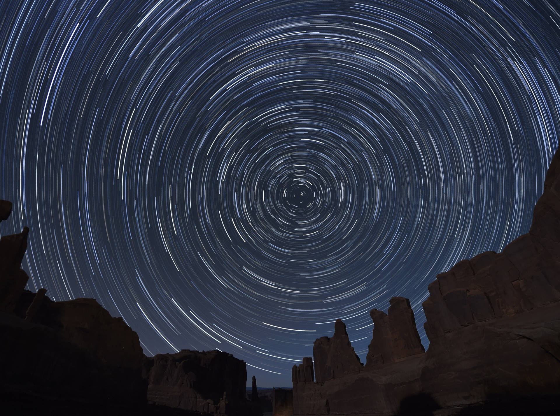 星軌在深藍色夜空下盤旋於沙漠岩石地貌之上。