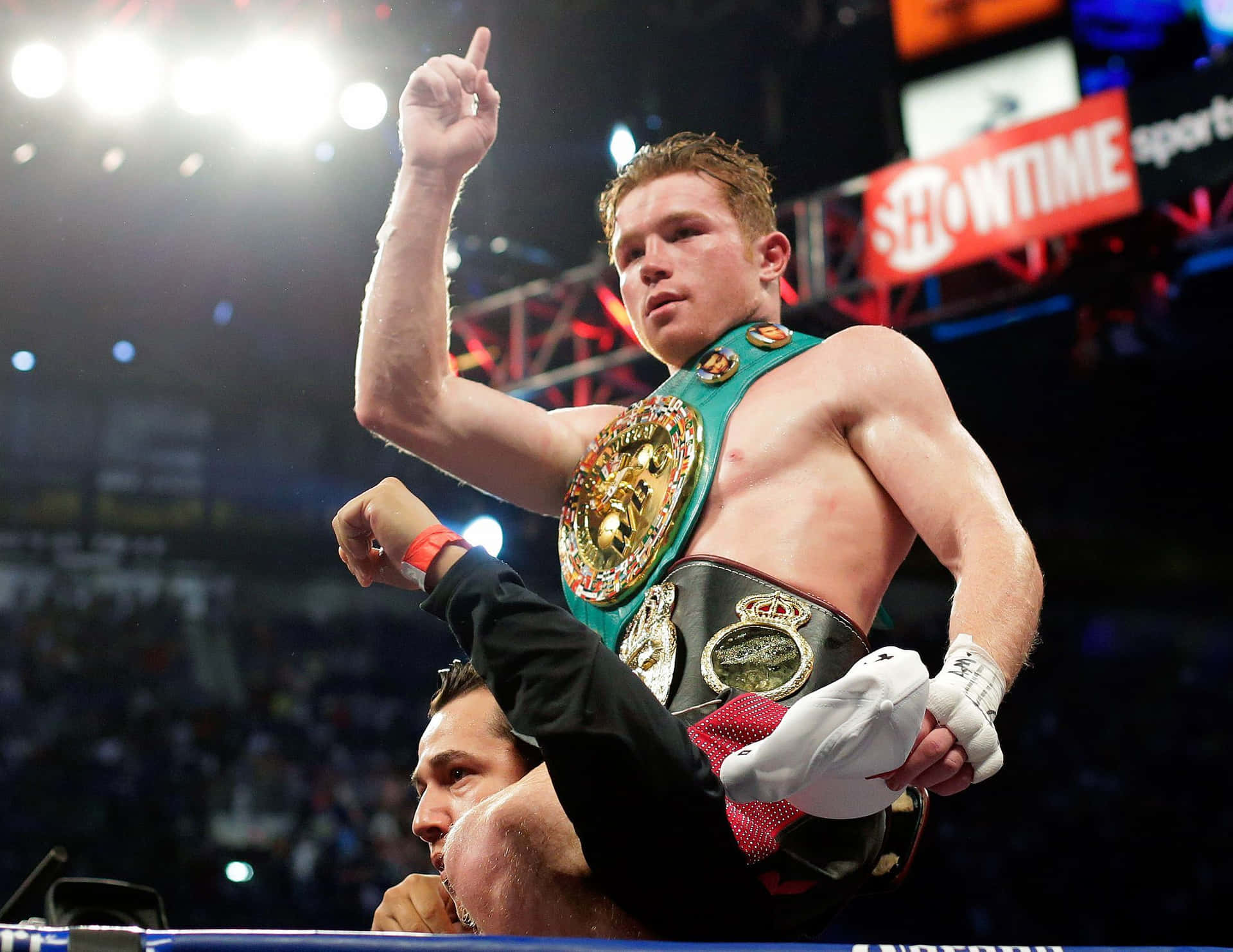 拳擊手Canelo Alvarez在擂台上帶著冠軍腰帶慶祝勝利。