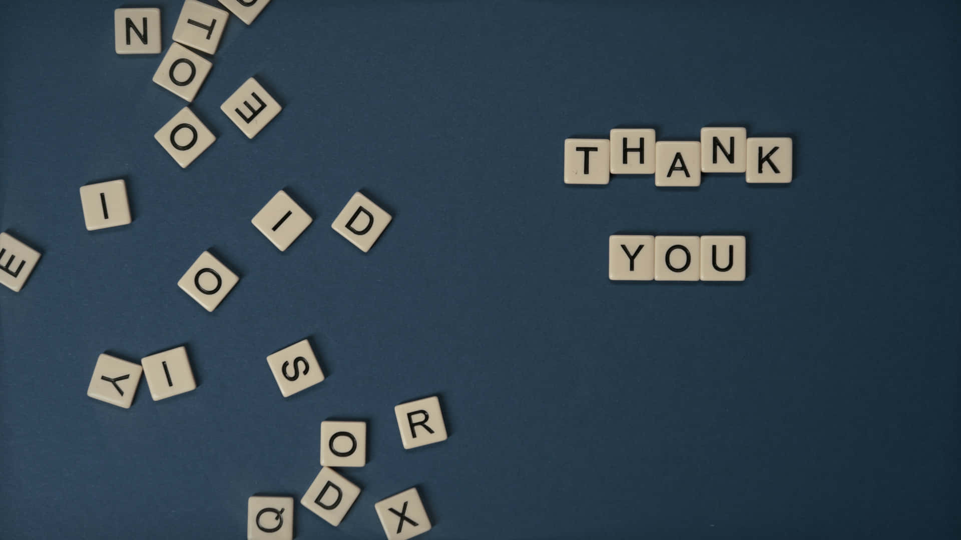 藍色背景上散落的白色字母瓷磚拼出「THANK YOU」和「NO ID」「SAY GOODBYE」