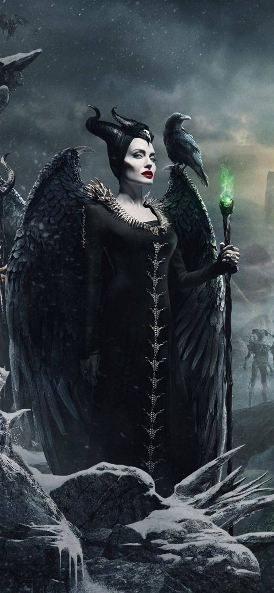 持杖魔法女與烏鴉 壁紙 — 一位黑翼女巫，紅唇，手持發光綠色法杖，站在風暴天空下的雪廢墟中。